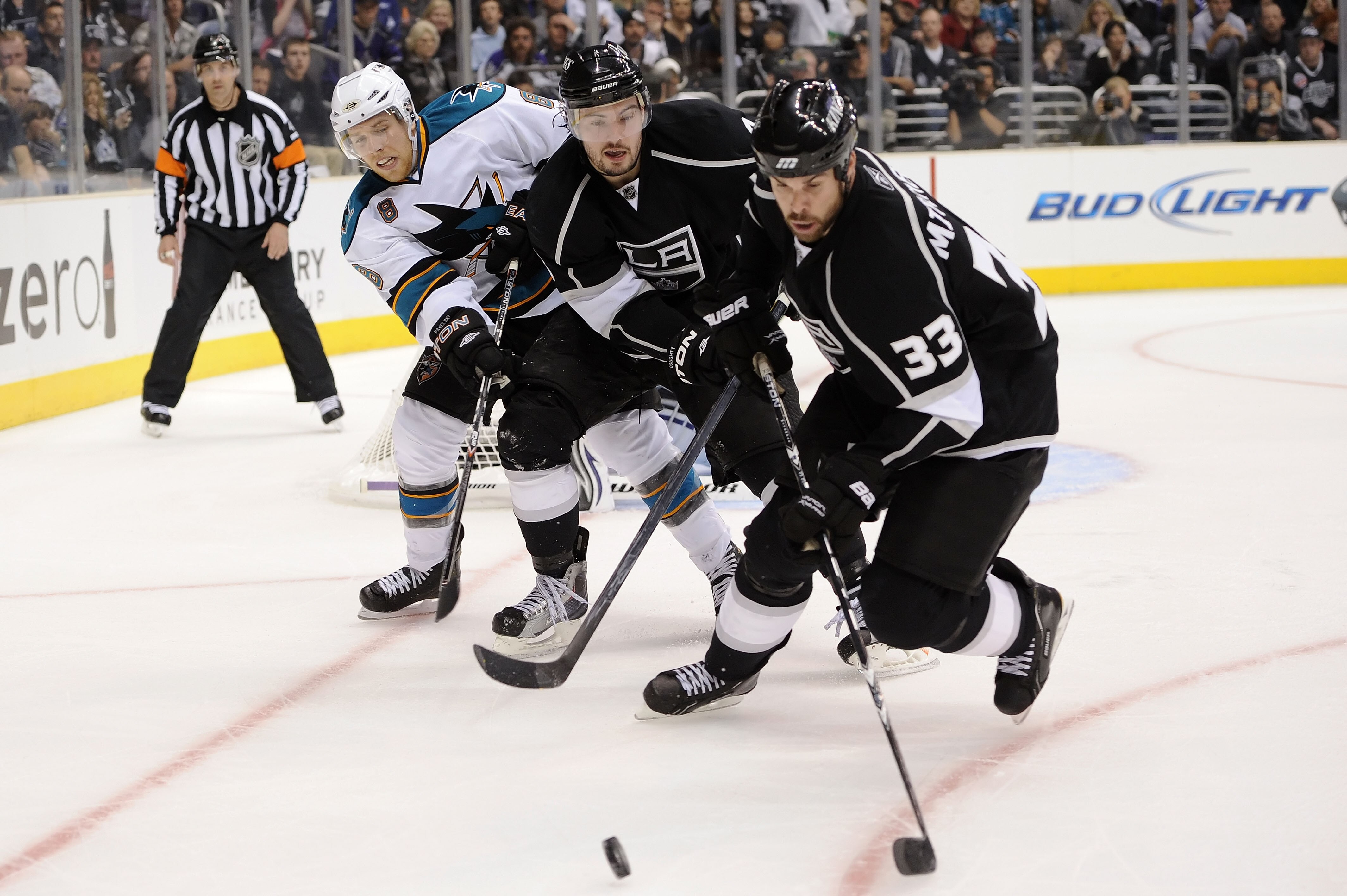 LOS ANGELES, CA - APRIL 19:  Willie Mitchell #33 and Drew Doughty #8 of the Los Angeles Kings control the puck away from Joe Pavelski #8 of the San Jose Sharks in game three of the Western Conference Quarterfinals during the 2011 NHL Stanley Cup Playoffs