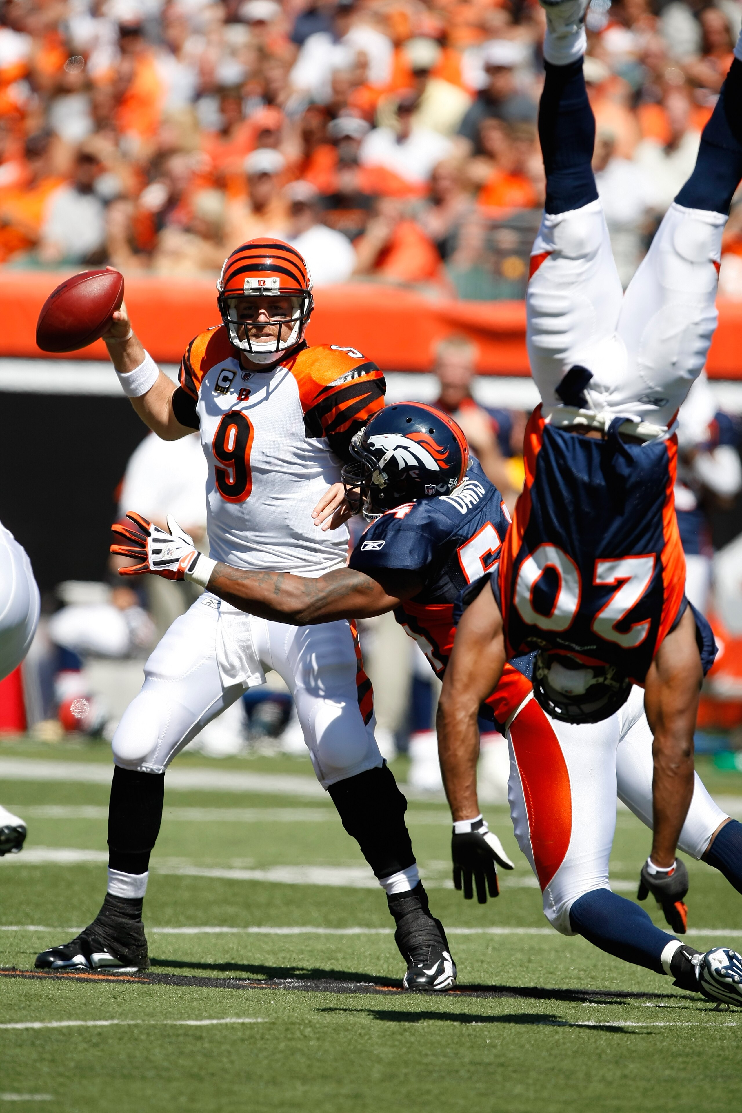 CINCINNATI, OH - SEPTEMBER 13: Quarterback Carson Palmer #9 of the Cincinnati Bengals is sacked by linebacker Andre Davis #54 of the Denver Broncos as defensive back Brian Dawkins #20 flips against the Denver Broncos at Paul Brown Stadium on September 13,