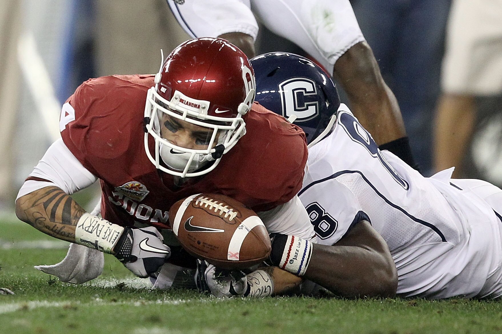 GLENDALE, AZ - JANUARY 01:  Kenny Stills #4 of the Oklahoma Sooners looses the football as he is hit by Lawrence Wilson #8 of the Connecticut Huskies but the Sooners recover in the first half during the Tostitos Fiesta Bowl at the Universtity of Phoenix S