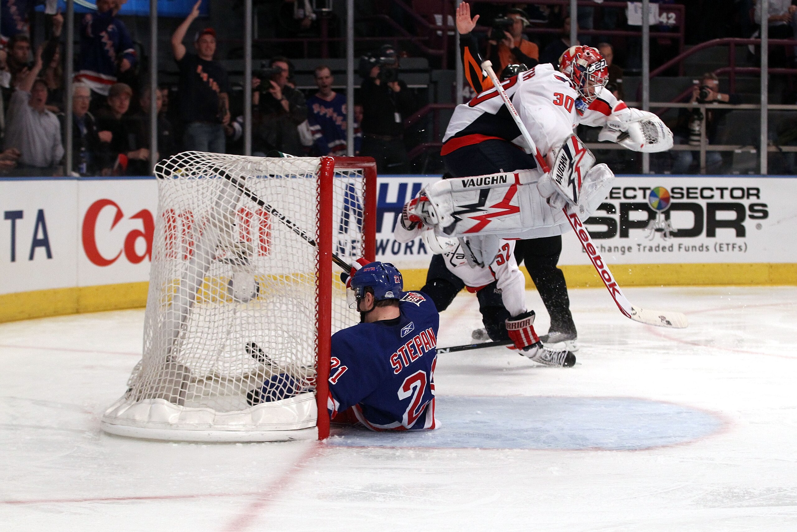 NEW YORK, NY - APRIL 20:  Goalie Michal Neuvirth #30 of the Washington Capitals jumps over Derek Stepan #21 of the New York Rangers as Stepan slides into the net in Game Four of the Eastern Conference Quarterfinals during the 2011 NHL Stanley Cup Playoffs