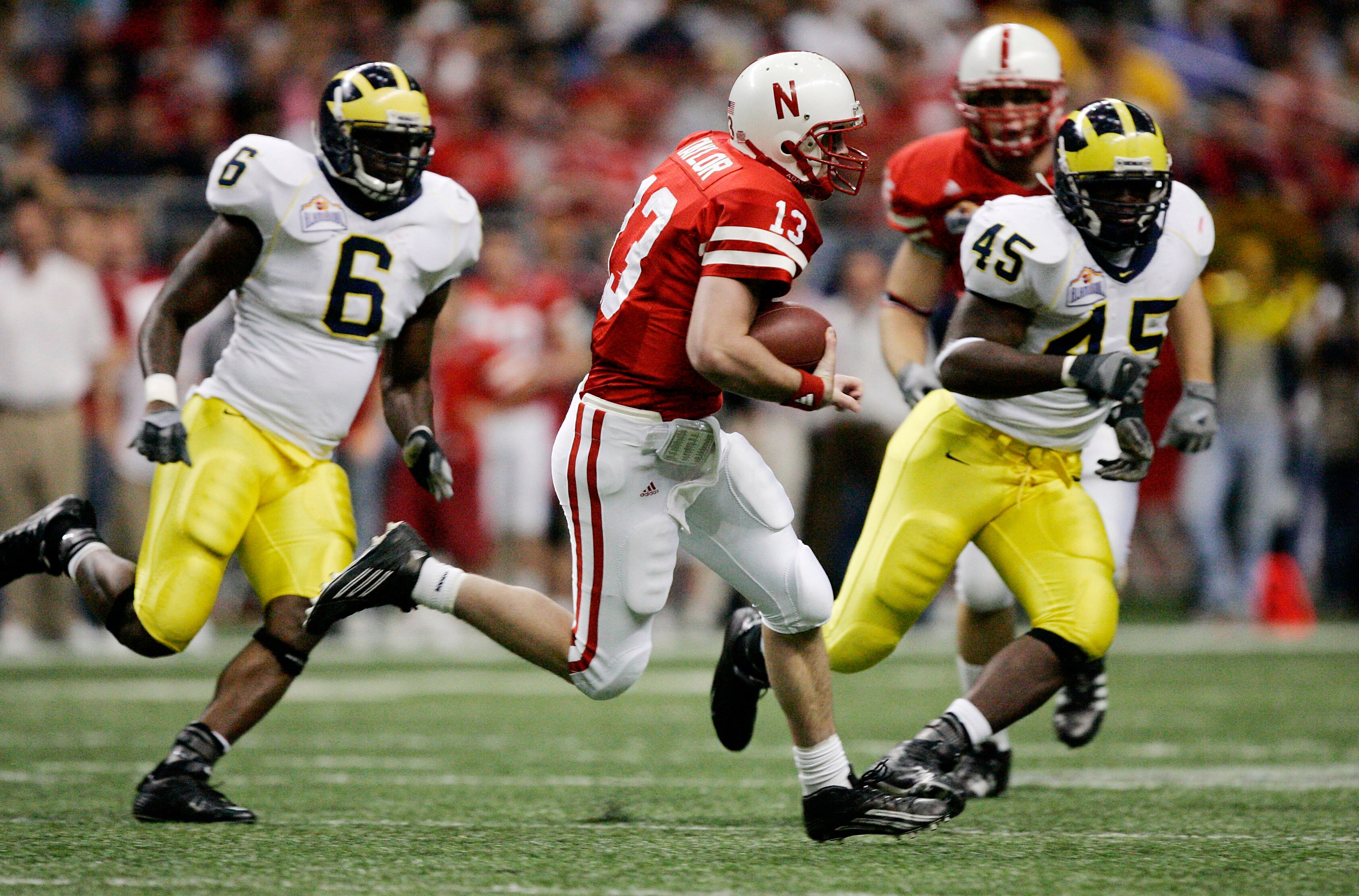 SAN ANTONIO - DECEMBER 28:  Quarterback Zac Taylor #13 of the Nebraska Cornhuskers breaks free for a big first down against Prescott Burgess #6 and Dave Harris #45 of the Michigan Wolverines during the first quarter of the MasterCard Alamo Bowl on Decembe