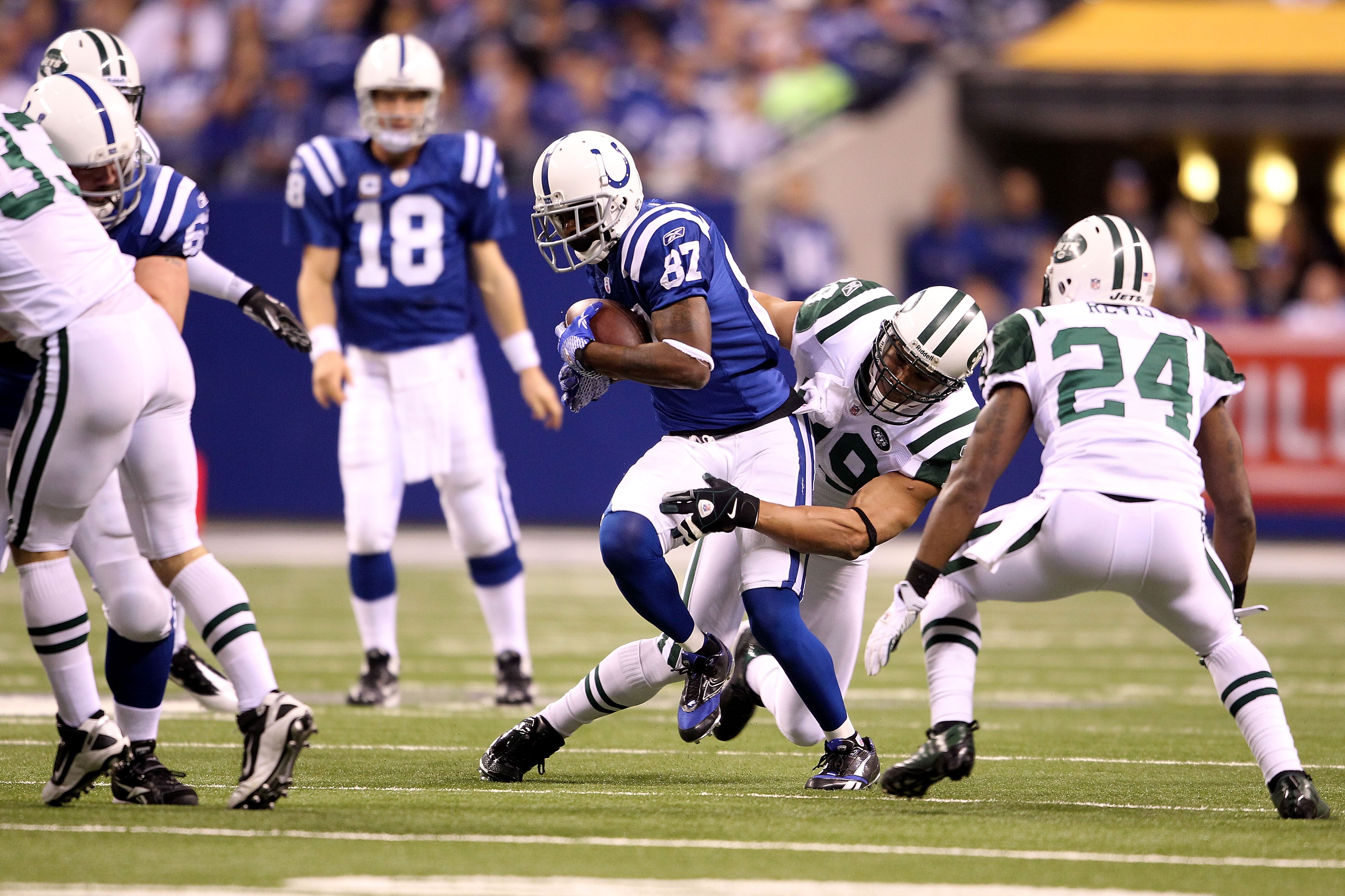 INDIANAPOLIS, IN - JANUARY 08:  Reggie Wayne #87 of the Indianapolis Colts is tackled as he makes a reception against Jason Taylor #99 and Darrelle Revis #24 of the New York Jets during their 2011 AFC wild card playoff game at Lucas Oil Stadium on January