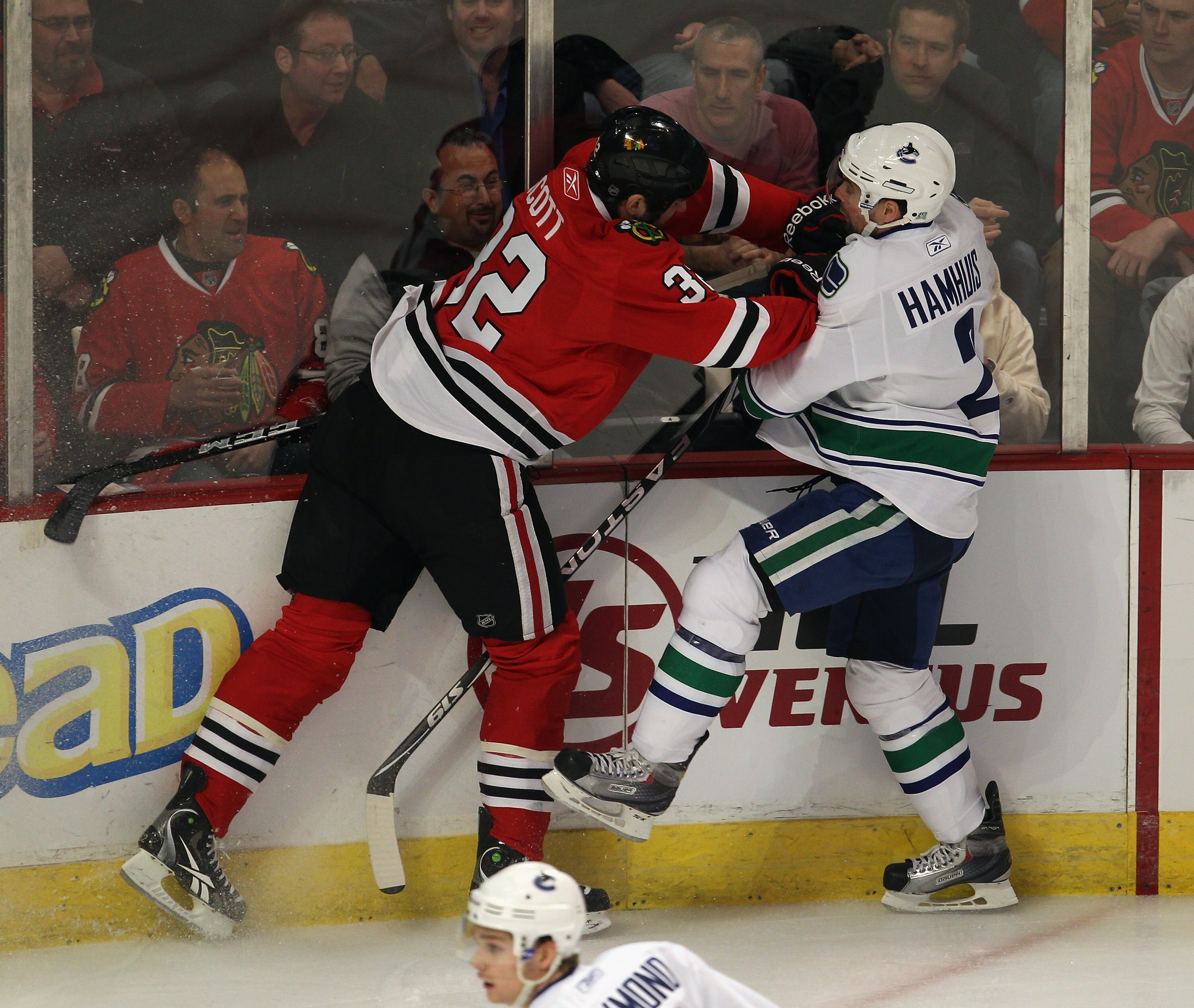 CHICAGO, IL - APRIL 17: John Scott #32 of the Chicago Blackhawks hits Dan Hamhuis #2 of the Vancouver Canucks in Game Three of the Western Conference Quarterfinals during the 2011 NHL Stanley Cup Playoffs at the United Center on April 17, 2011 in Chicago,