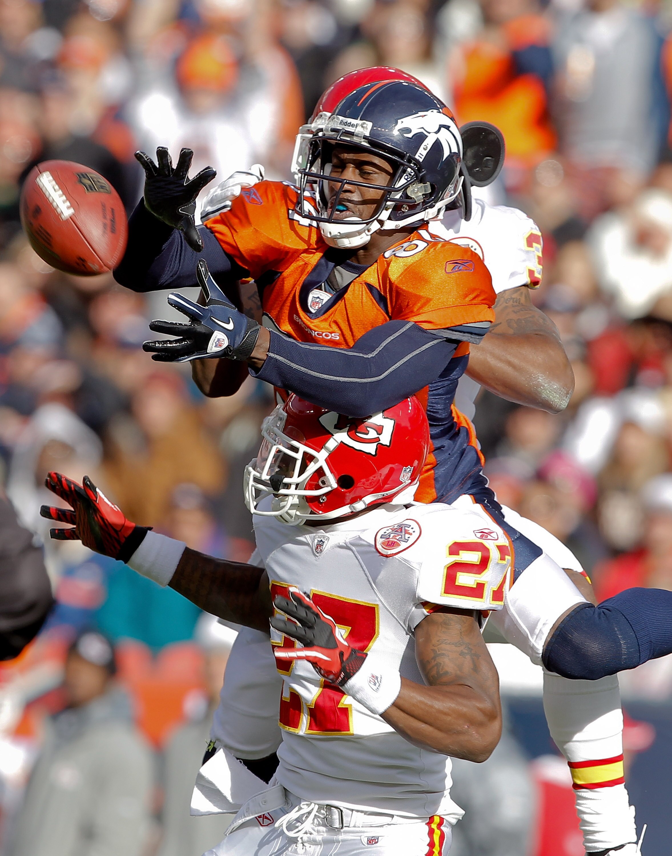 DENVER - NOVEMBER 14:  Wide receiver Brandon Lloyd #84 of the Denver Broncos makes a reception for a first down against cornerback Donald Washington #27 of the Kansas City Chiefs and teammate cornerback Brandon Carr #39 in the first quarter at INVESCO Fie