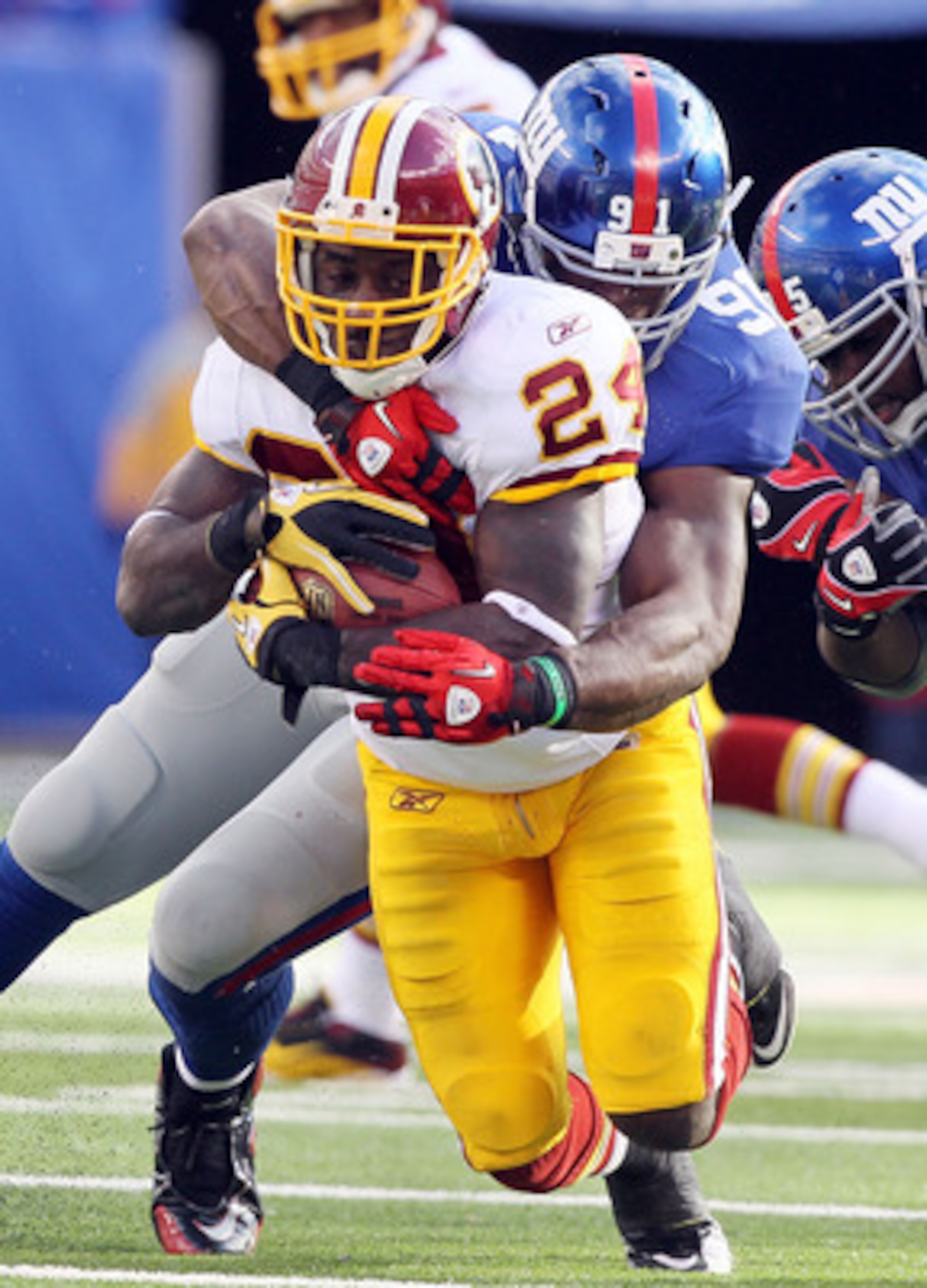 EAST RUTHERFORD, NJ - DECEMBER 05:  James Davis #24 of the Washington Redskins is tackled by Justin Tuck #91 of the New York Giants on December 5, 2010 at the New Meadowlands Stadium in East Rutherford, New Jersey.  (Photo by Jim McIsaac/Getty Images)