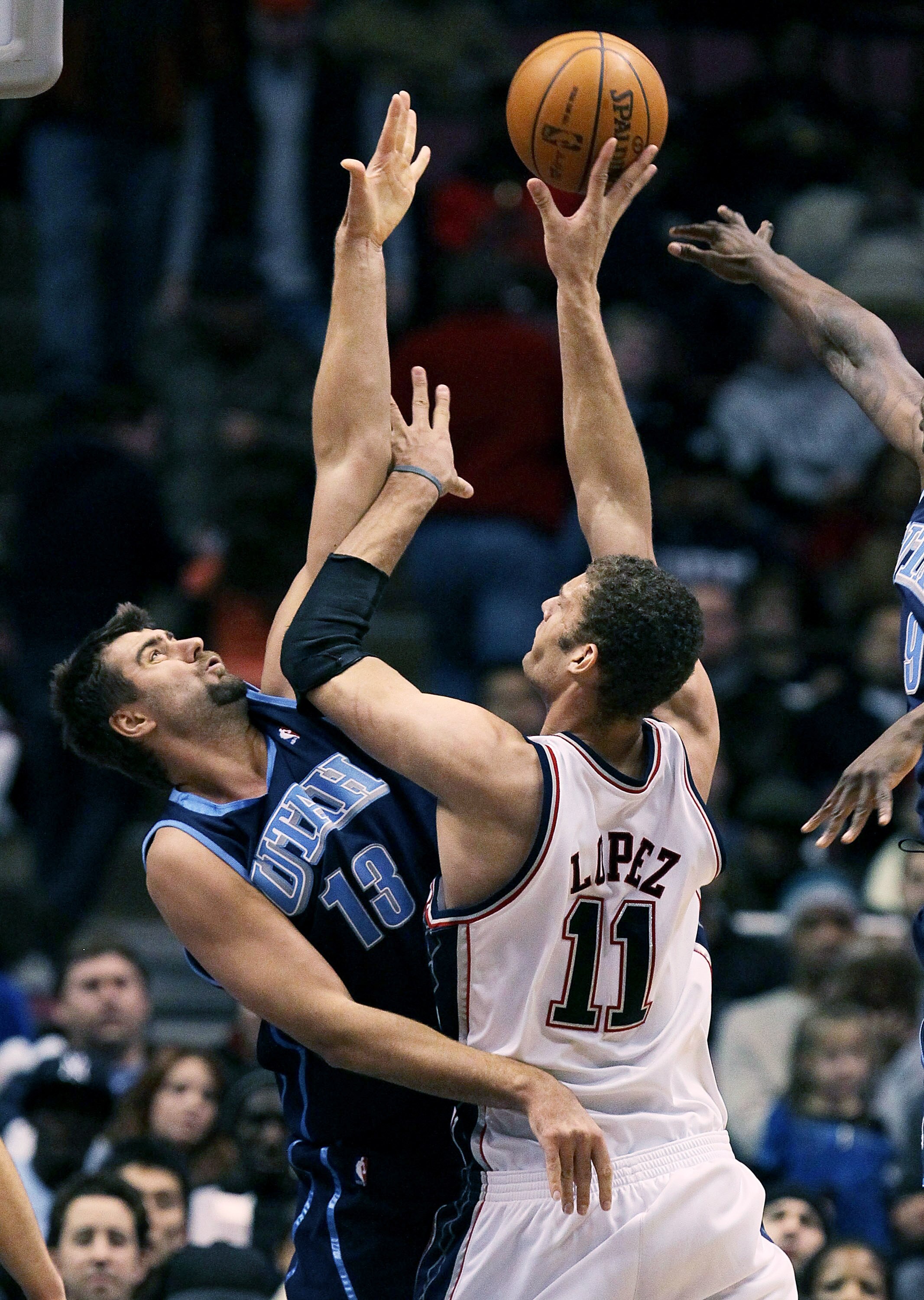 EAST RUTHERFORD, NJ - DECEMBER 16:  Brook Lopez #11 of the New Jersey Nets shoots over Mehmet Okur #13 of the Utah Jazz during their game on December 16, 2009 at the IZOD Center in East Rutherford, New Jersey.  NOTE TO USER: User expressly acknowledges an