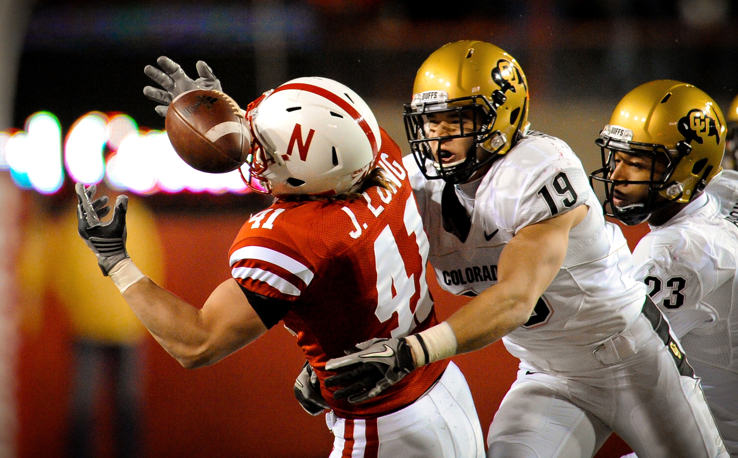 LINCOLN, NE - NOVEMBER 26: Jake Long #41 of the Nebraska Cornhuskers catches a pass over Travis Sandersfeld #19 and Jalil Brown #23 of the Colorado Buffaloes during the second half of their game at Memorial Stadium on November 26, 2010 in Lincoln, Nebrask LINCOLN, NE - NOVEMBER 26: Jake Long #41 of the Nebraska Cornhuskers catches a pass over Travis Sandersfeld #19 and Jalil Brown #23 of the Colorado Buffaloes during the second half of their game at Memorial Stadium on November 26, 2010 in Lincoln, Nebrask