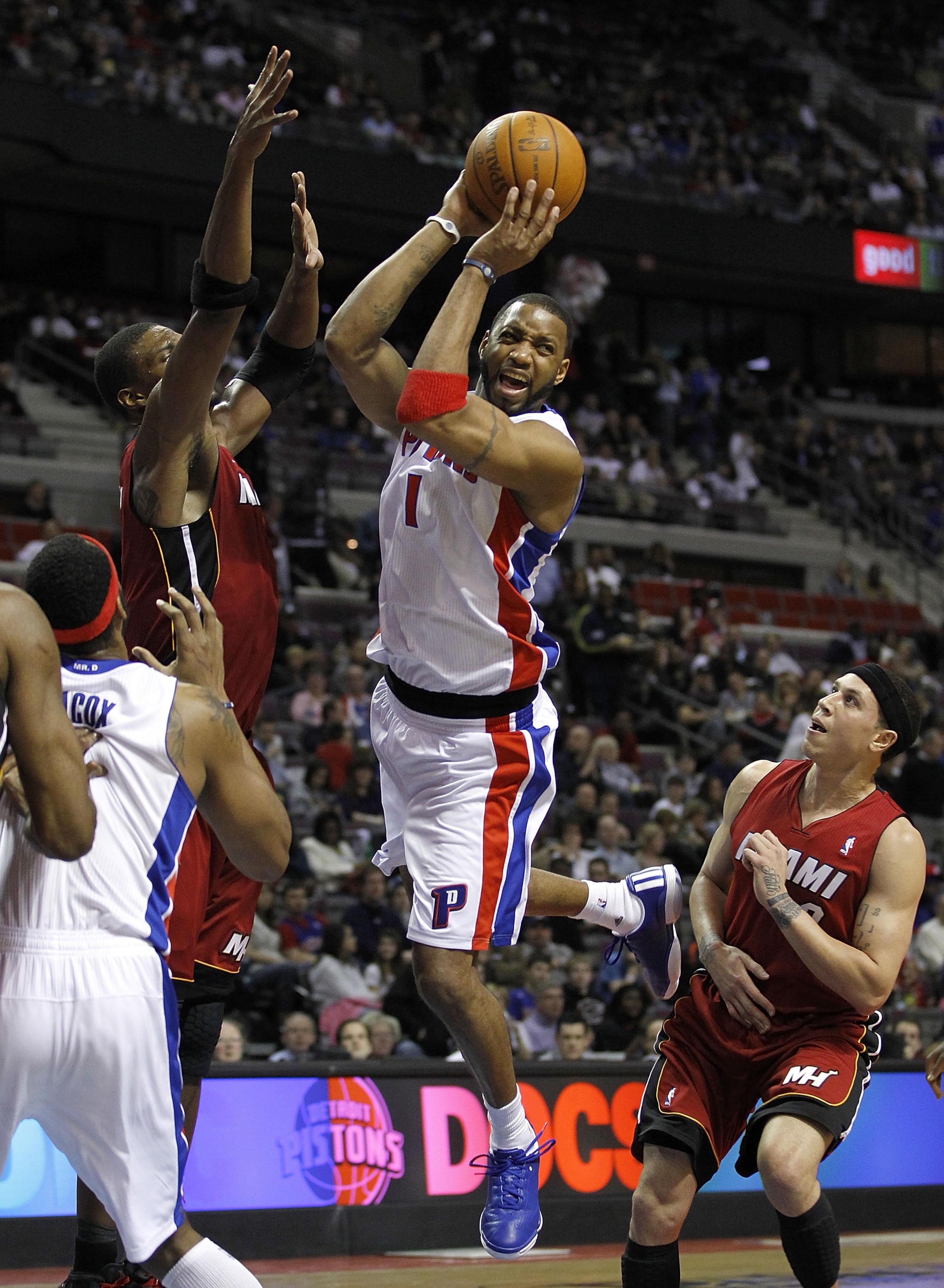 AUBURN HILLS, MI - MARCH 23:  Tracy McGrady #1 of the Detroit Pistons looks for an open teammate between Mike Bibby #0 and Dwyane Wade #3 of the Miami Heat at The Palace of Auburn Hills on March 23, 2011 in Auburn Hills, Michigan. Miami won the game 100-9