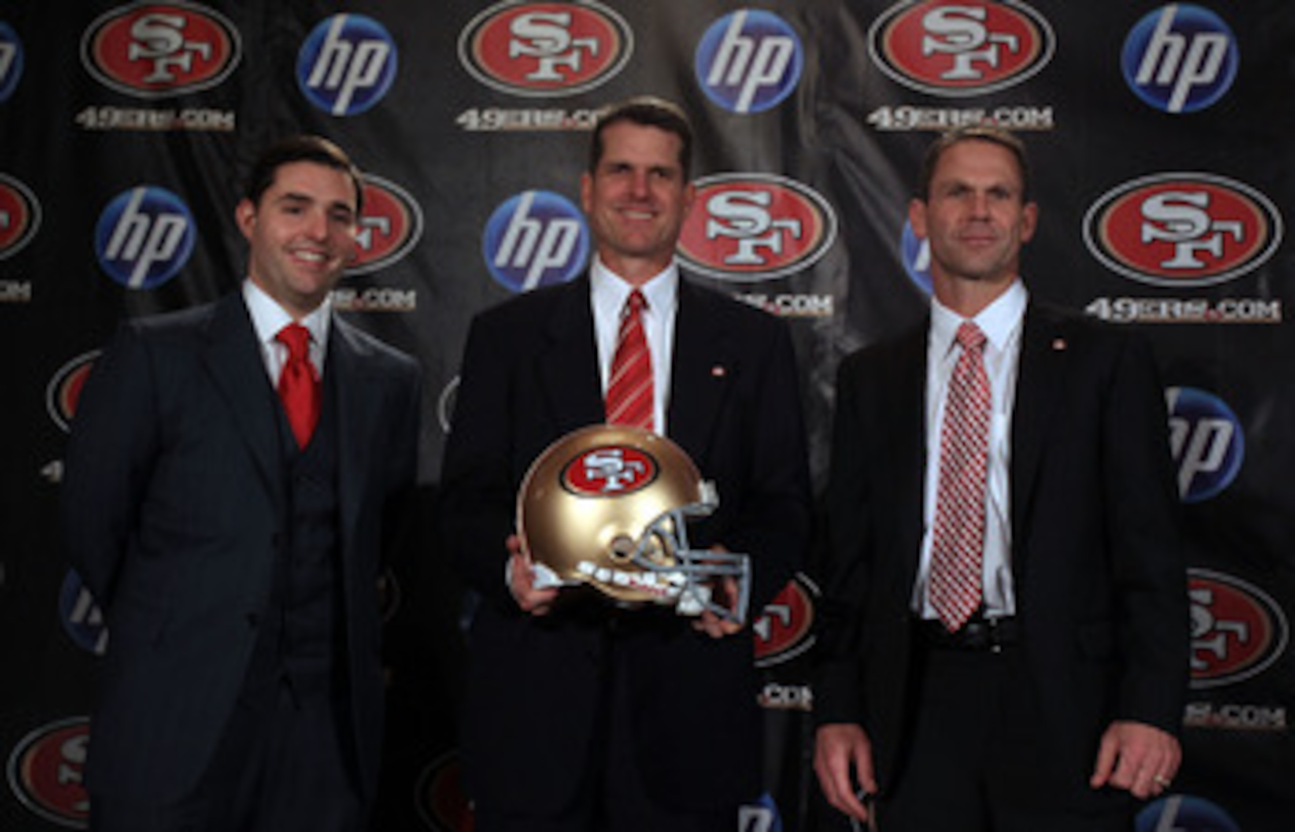 SAN FRANCISCO, CA - JANUARY 07:  Jim Harbaugh poses for a picture with President and CEO of the San Francisco 49ers, Jed York, (left) and general manager Trent Baalk following a press conference where Harbaugh was introduced as the new San Francisco 49ers