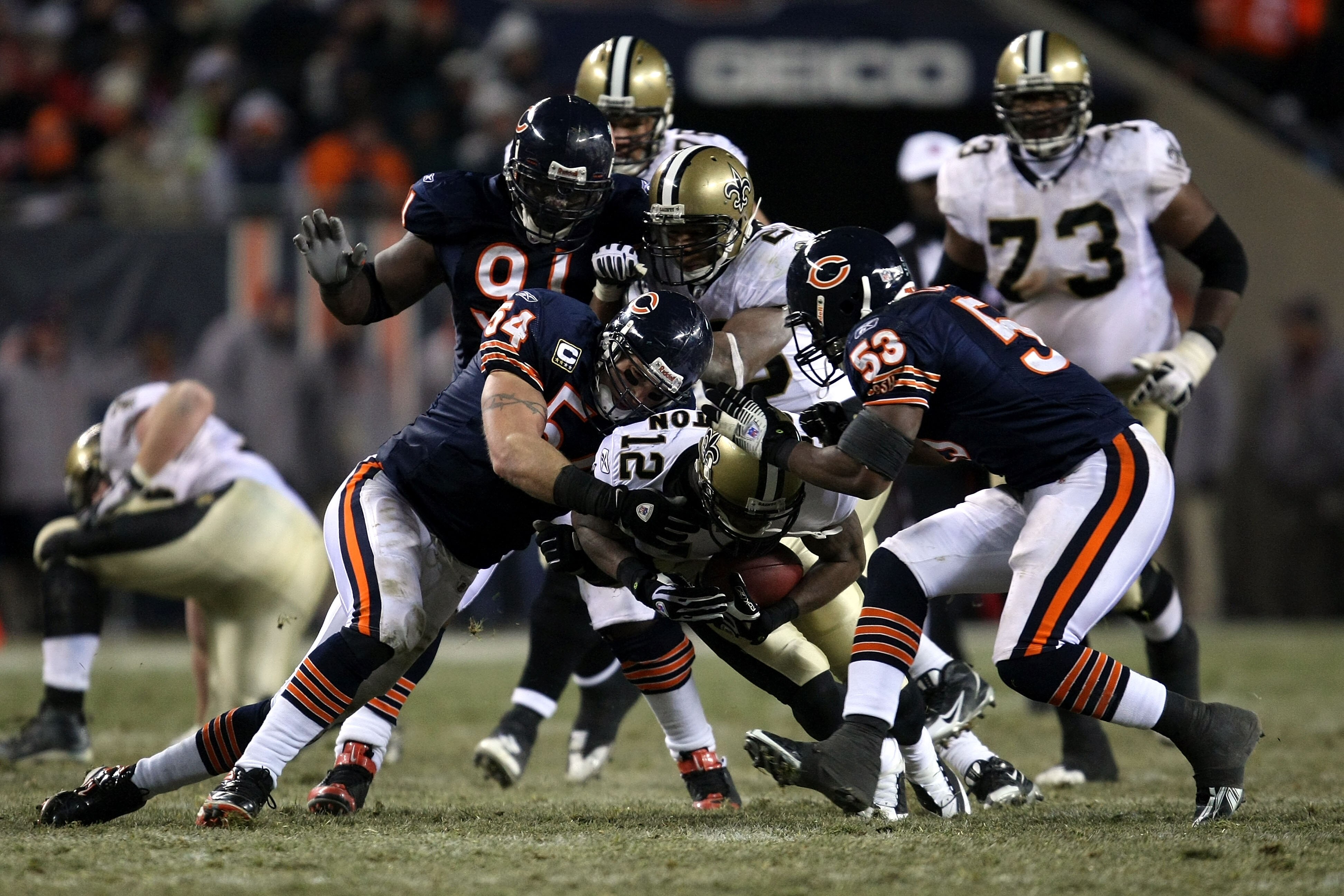 CHICAGO - DECEMBER 11:  Marques Colston #12 of the New Orleans Saints is tackled by Brian Urlacher #54, Tommie Harris #91 and Nick Roach #53 of the Chicago Bears at Soldier Field on December 11, 2008 in Chicago, Illinois. The Bears won 27-24. (Photo by Jo