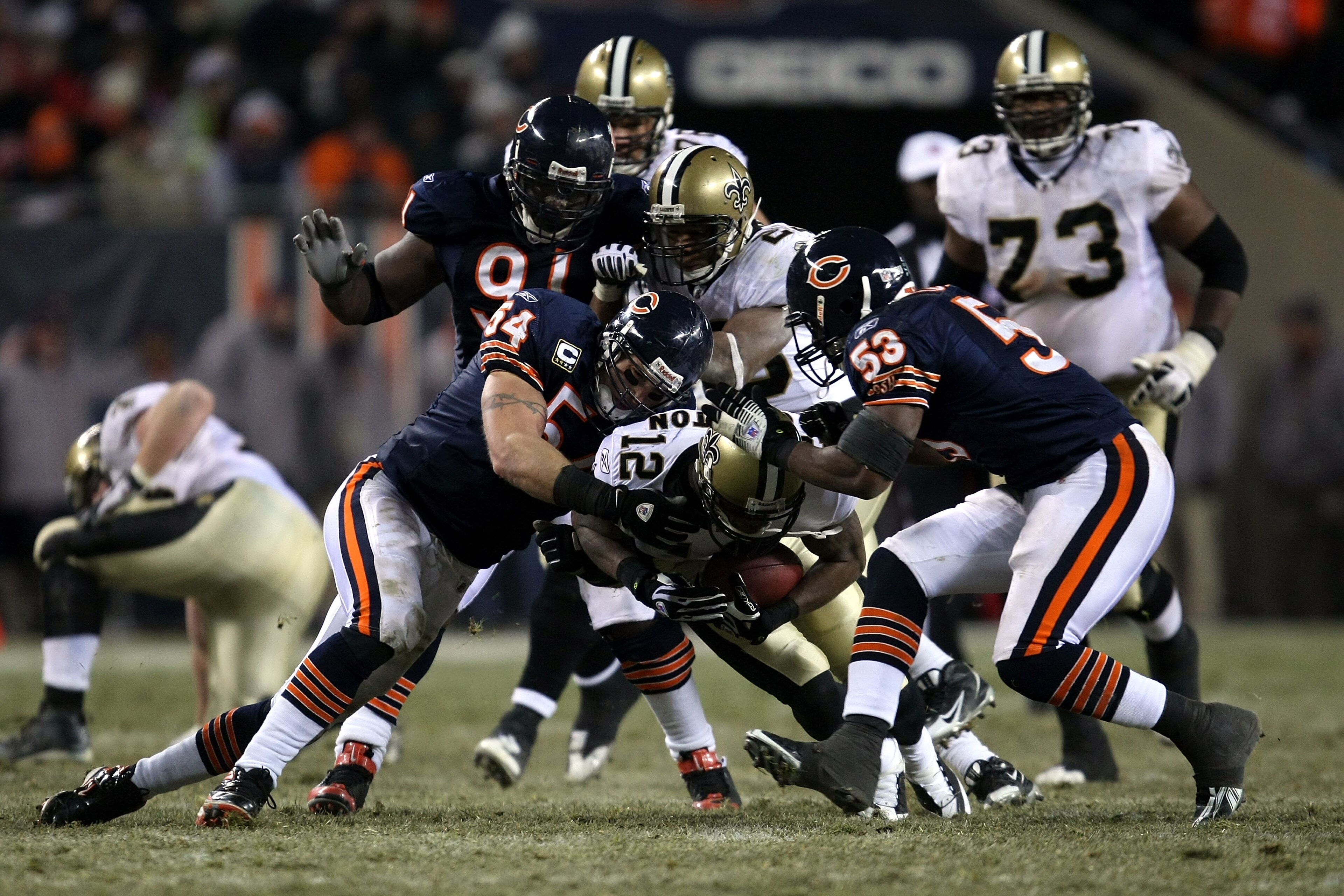 CHICAGO - DECEMBER 11:  Marques Colston #12 of the New Orleans Saints is tackled by Brian Urlacher #54, Tommie Harris #91 and Nick Roach #53 of the Chicago Bears at Soldier Field on December 11, 2008 in Chicago, Illinois. The Bears won 27-24. (Photo by Jo