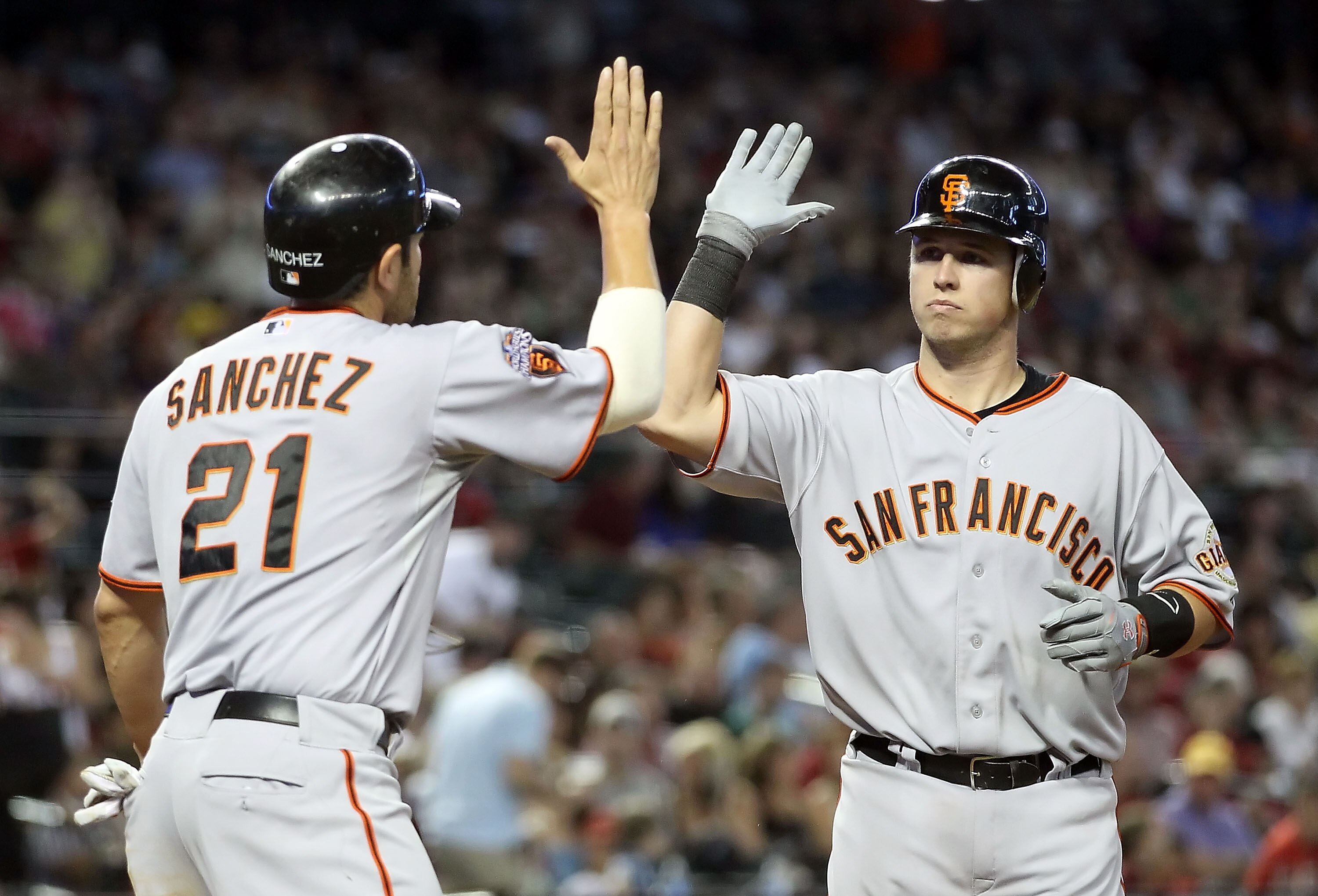 PHOENIX, AZ - APRIL 17:  Buster Posey #28 of the San Francisco Giants high fives teammate Freddy Sanchez #21 after Posey hit a two run home run against the Arizona Diamondbacks during the sixth inning of the Major League Baseball game at Chase Field on Ap