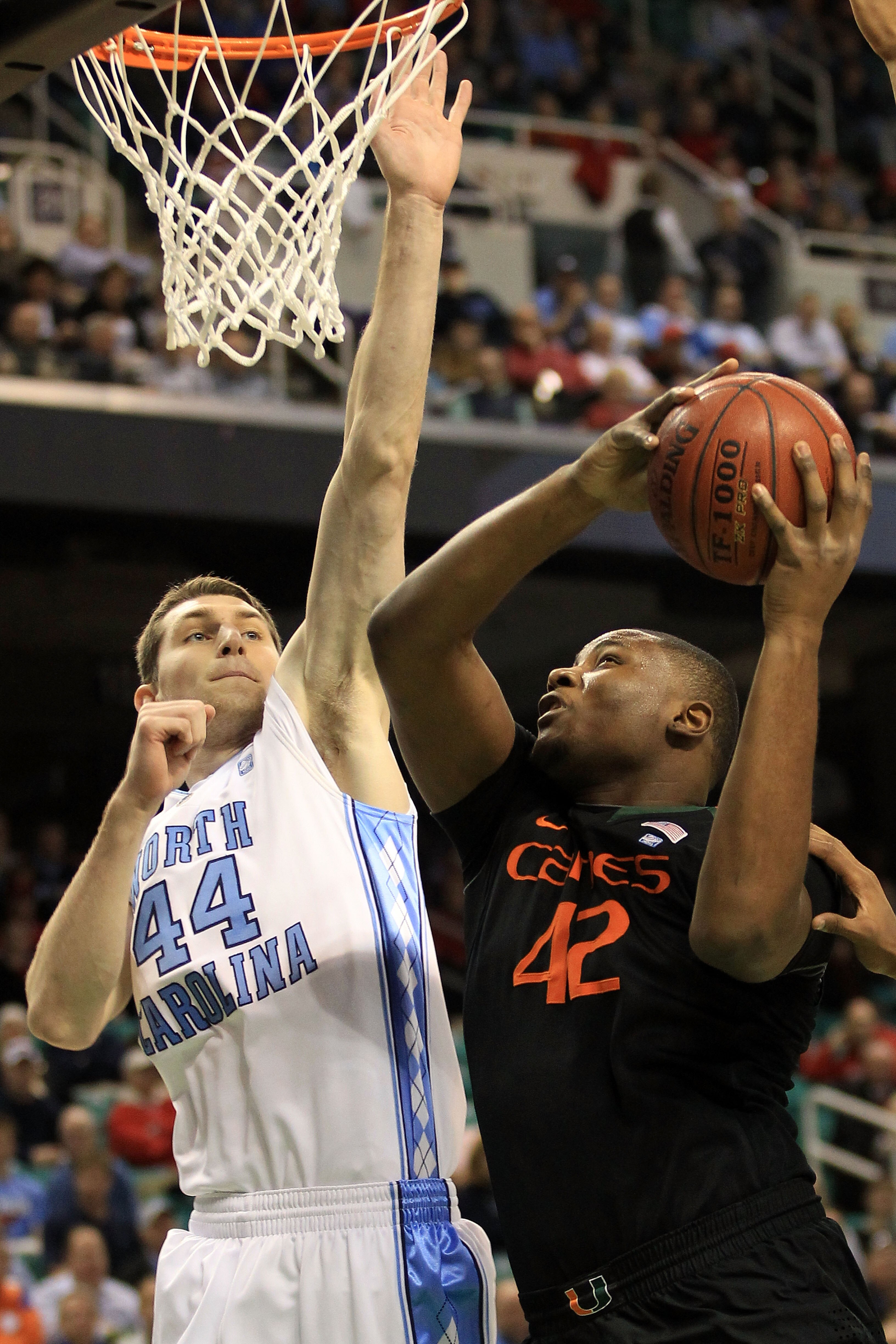 GREENSBORO, NC - MARCH 11:  Reggie Johnson #42 of the Miami Hurricanes shoots against Tyler Zeller #44 of the North Carolina Tar Heels during the first half in the quarterfinals of the 2011 ACC men's basketball tournament at the Greensboro Coliseum on Mar