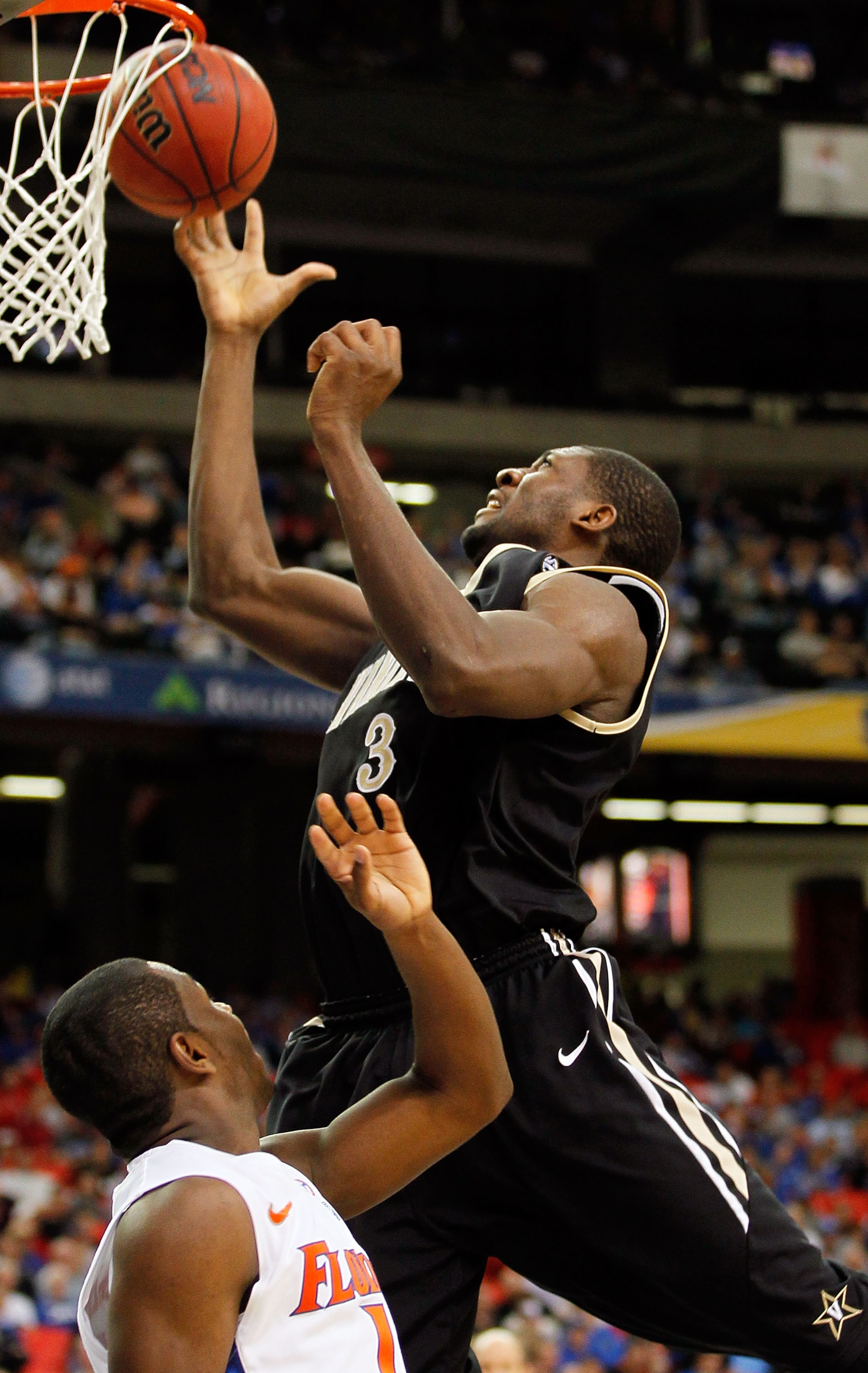 ATLANTA, GA - MARCH 12:  Festus Ezeli #3 of the Vanderbilt Commodores goes up for a shot against Erving Walker #11 of the Florida Gators during the semifinals of the SEC Men's Basketball Tournament at Georgia Dome on March 12, 2011 in Atlanta, Georgia.  (