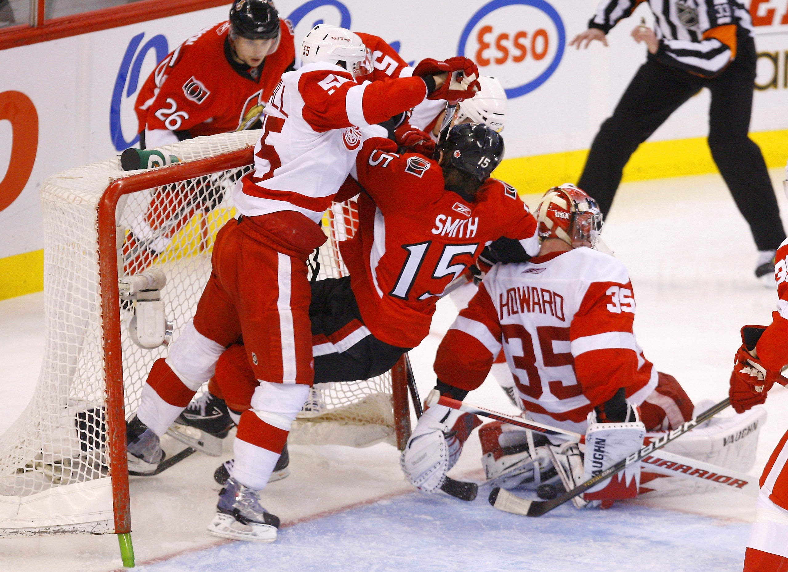 OTTAWA, ON - FEBRUARY 02:  Zack Smith #15 of the Ottawa Senators gets knocked down in the crease by Nicklas Kronwall #55 of the Detroit Red Wings while teammate Jimmy Howard #35 tries to cover up a loose puck in a game at Scotiabank Place on February 2, 2