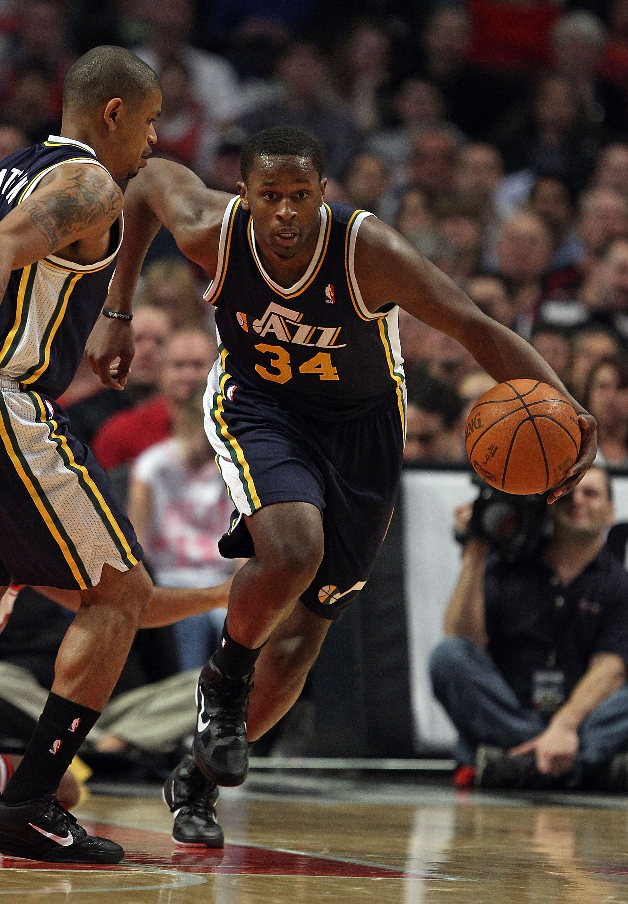 CHICAGO, IL - MARCH 12: C.J. Miles #34 of the Utah Jazz moves up the court past teammate Earl Watson #11 against the Chicago Bulls at the United Center on March 12, 2011 in Chicago, Illinois. The Bulls defeated the Jazz 118-100. NOTE TO USER: User express