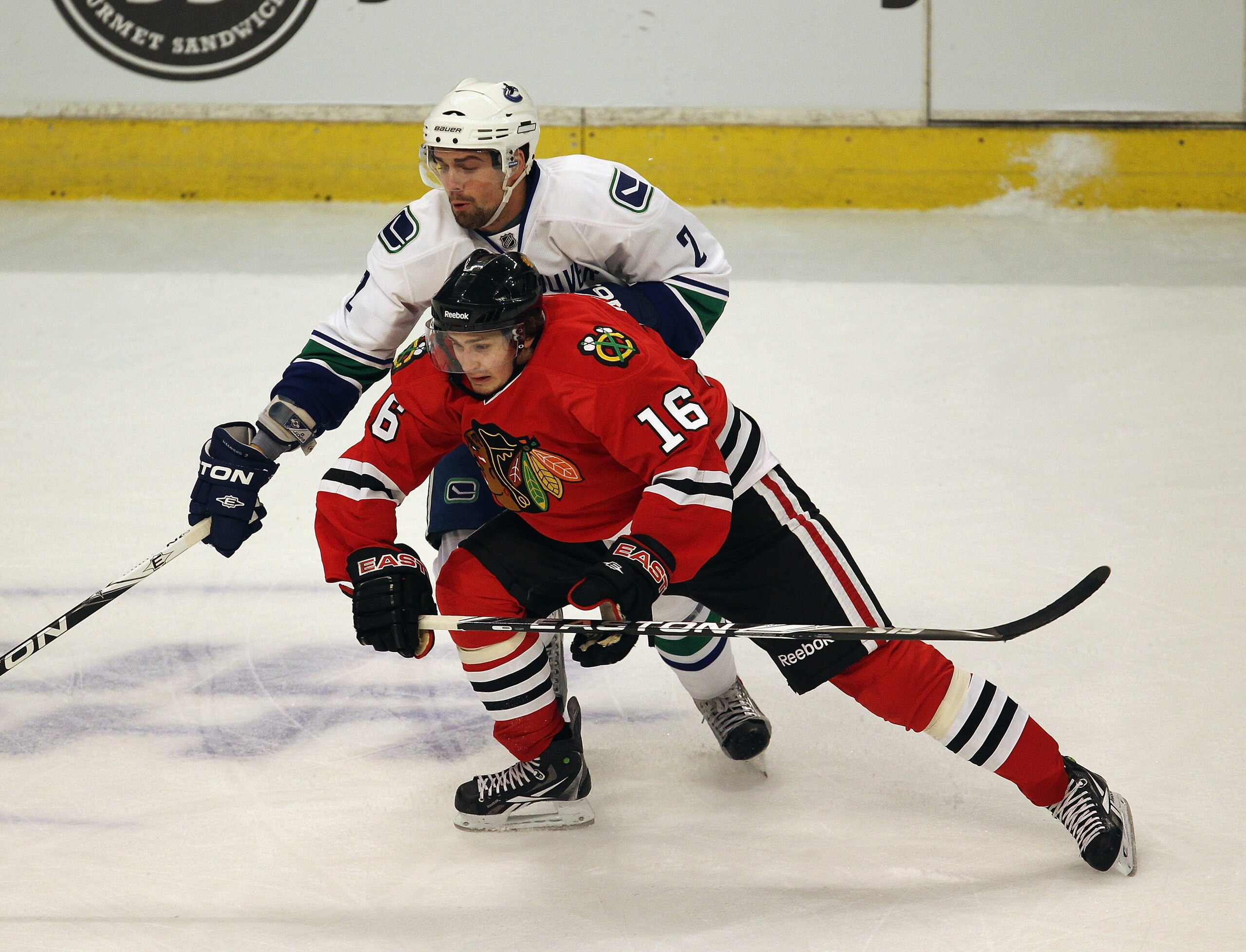 CHICAGO, IL - APRIL 17: Marcus Kruger #16 of the Chicago Blackhawks and Dan Hamhuis #2 of the Vancouver Canucks skate to the puck in Game Three of the Western Conference Quarterfinals during the 2011 NHL Stanley Cup Playoffs at the United Center on April