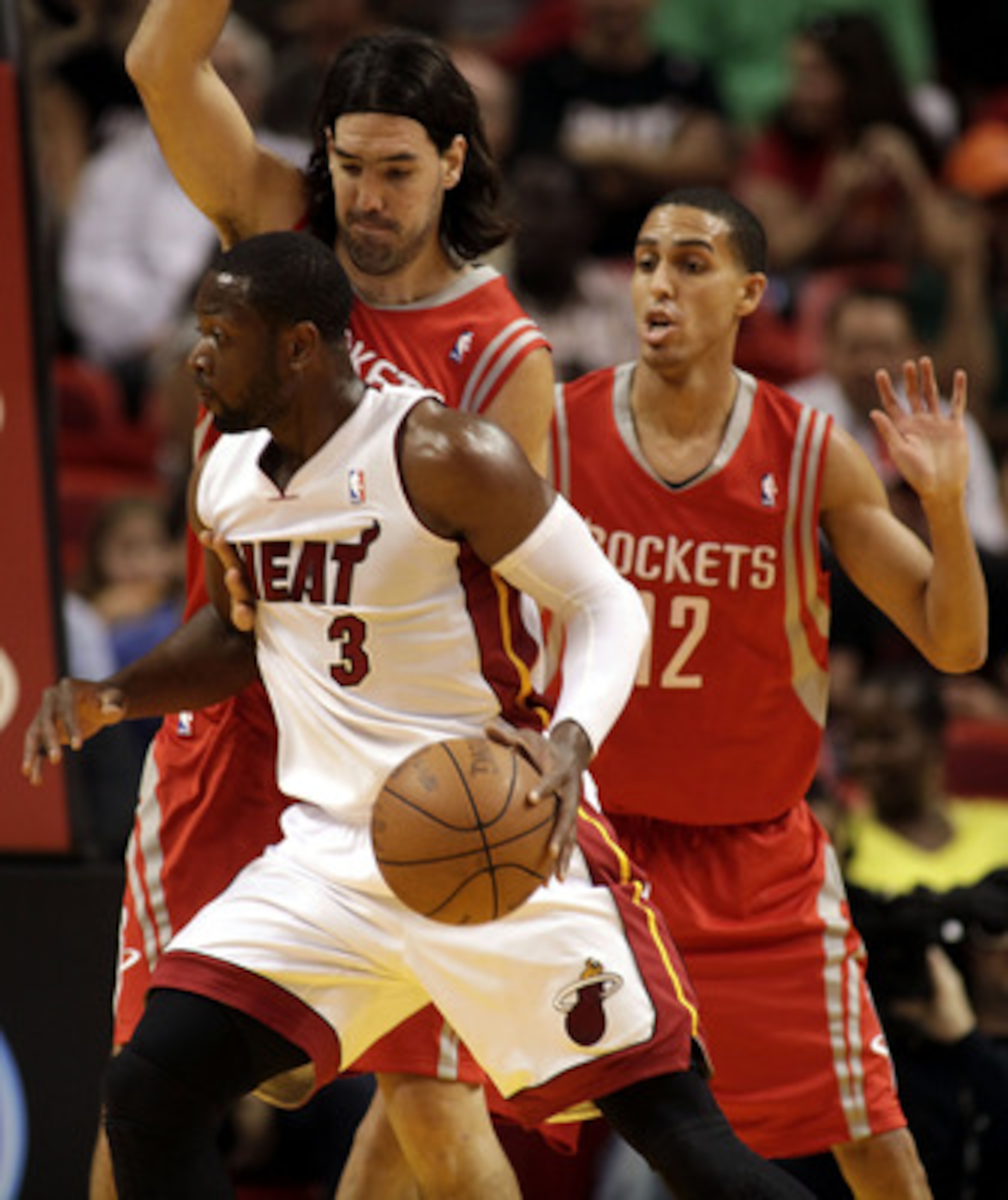 MIAMI, FL - MARCH 27:  Guard Dwyane Wade of the Miami Heat drives against gurad Kevin Martin #12 and forward Luis Scola #4 of the Houston Rockets at American Airlines Arena on March 27, 2011 in Miami, Florida. NOTE TO USER: User expressly acknowledges and