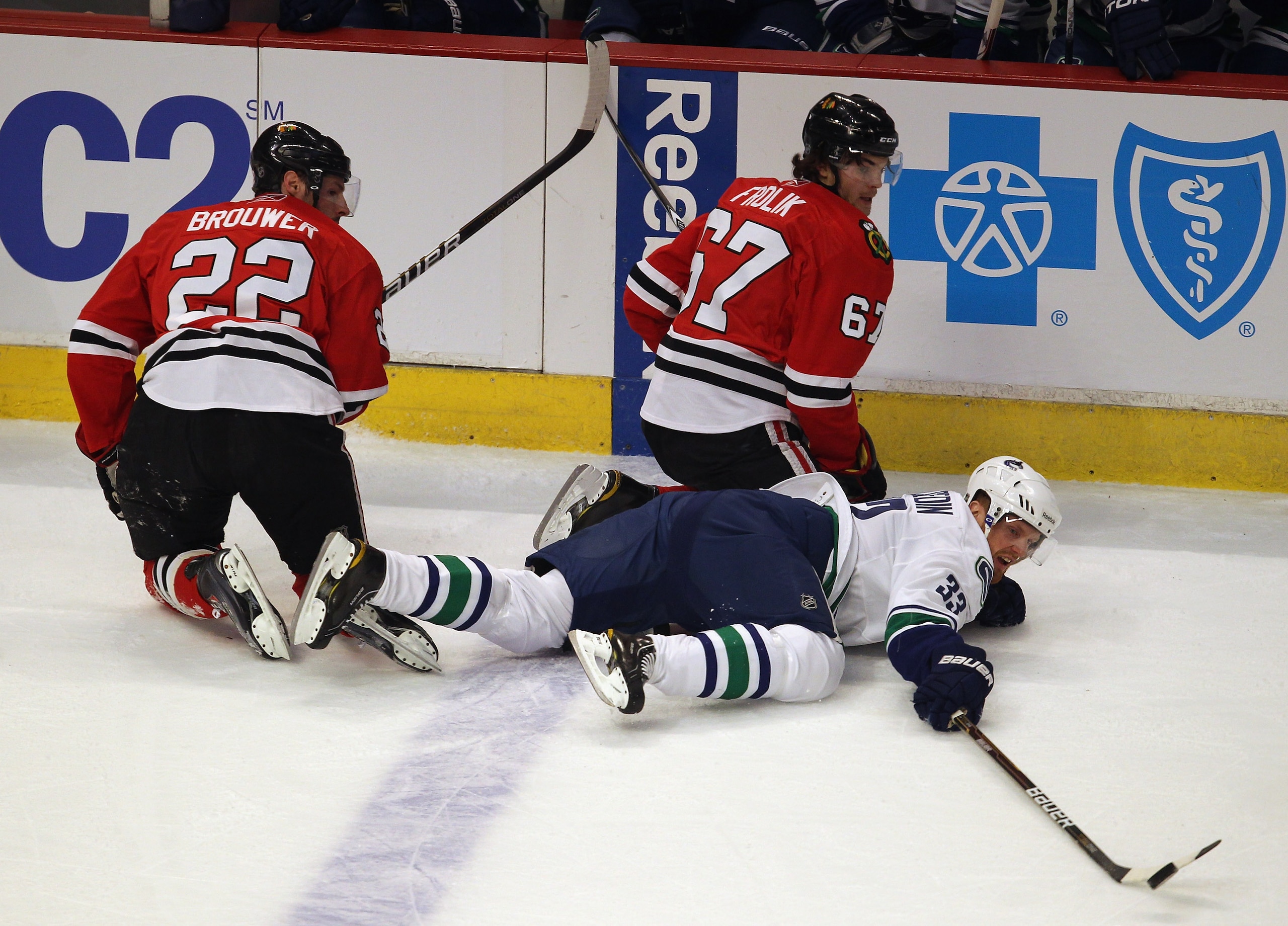 CHICAGO, IL - APRIL 17: Henrik Sedin #33 of the Vancouver Canucks knocks away the puck from Troy Brouwer #22 and Michael Frolik #67 of the Chicago Blackhawks in Game Three of the Western Conference Quarterfinals during the 2011 NHL Stanley Cup Playoffs at CHICAGO, IL - APRIL 17: Henrik Sedin #33 of the Vancouver Canucks knocks away the puck from Troy Brouwer #22 and Michael Frolik #67 of the Chicago Blackhawks in Game Three of the Western Conference Quarterfinals during the 2011 NHL Stanley Cup Playoffs at