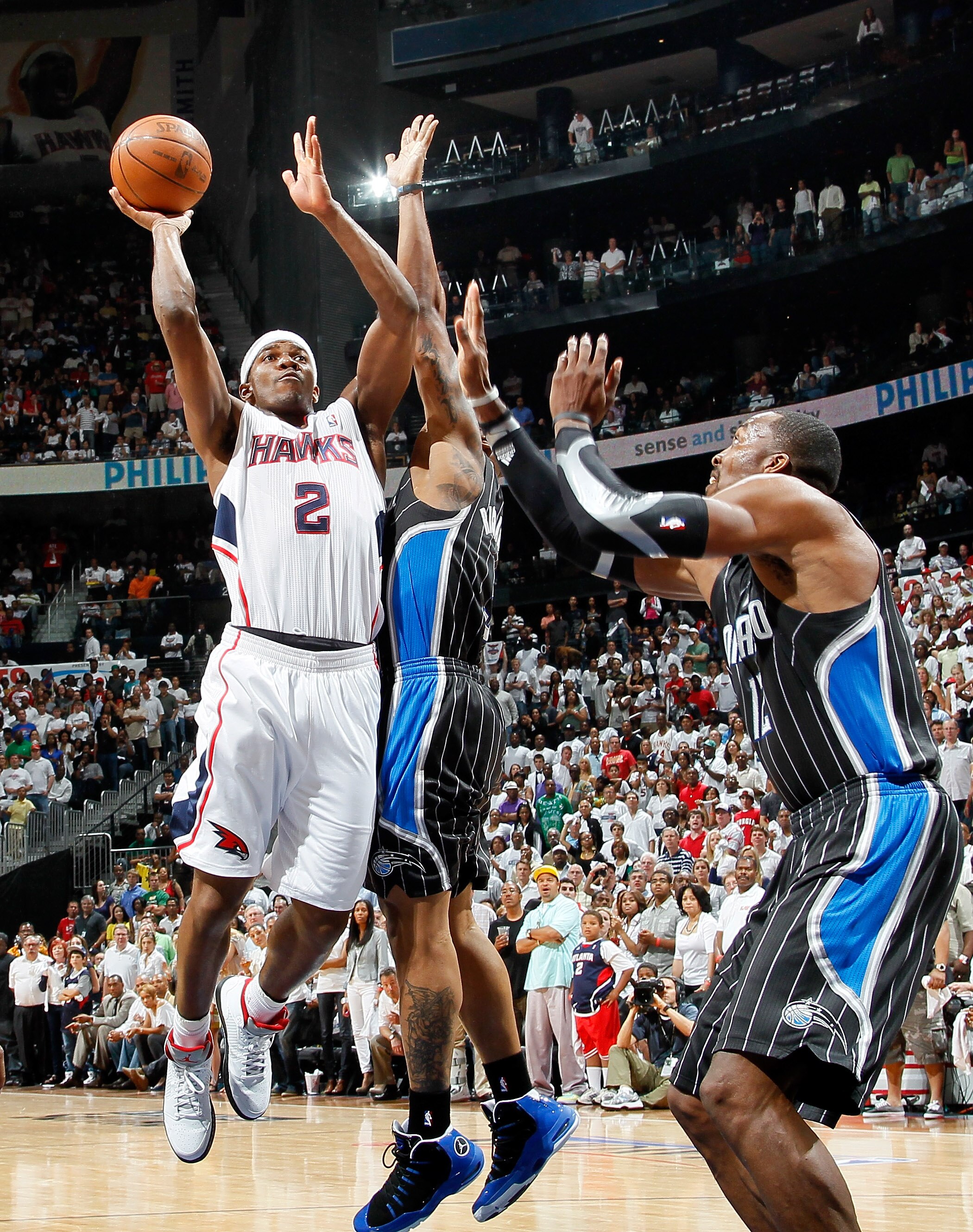ATLANTA, GA - APRIL 24:  Joe Johnson #2 of the Atlanta Hawks shoots against Quentin Richardson #5 and Dwight Howard #12 of the Orlando Magic during Game Four of the Eastern Conference Quarterfinals in the 2011 NBA Playoffs at Philips Arena on April 24, 20
