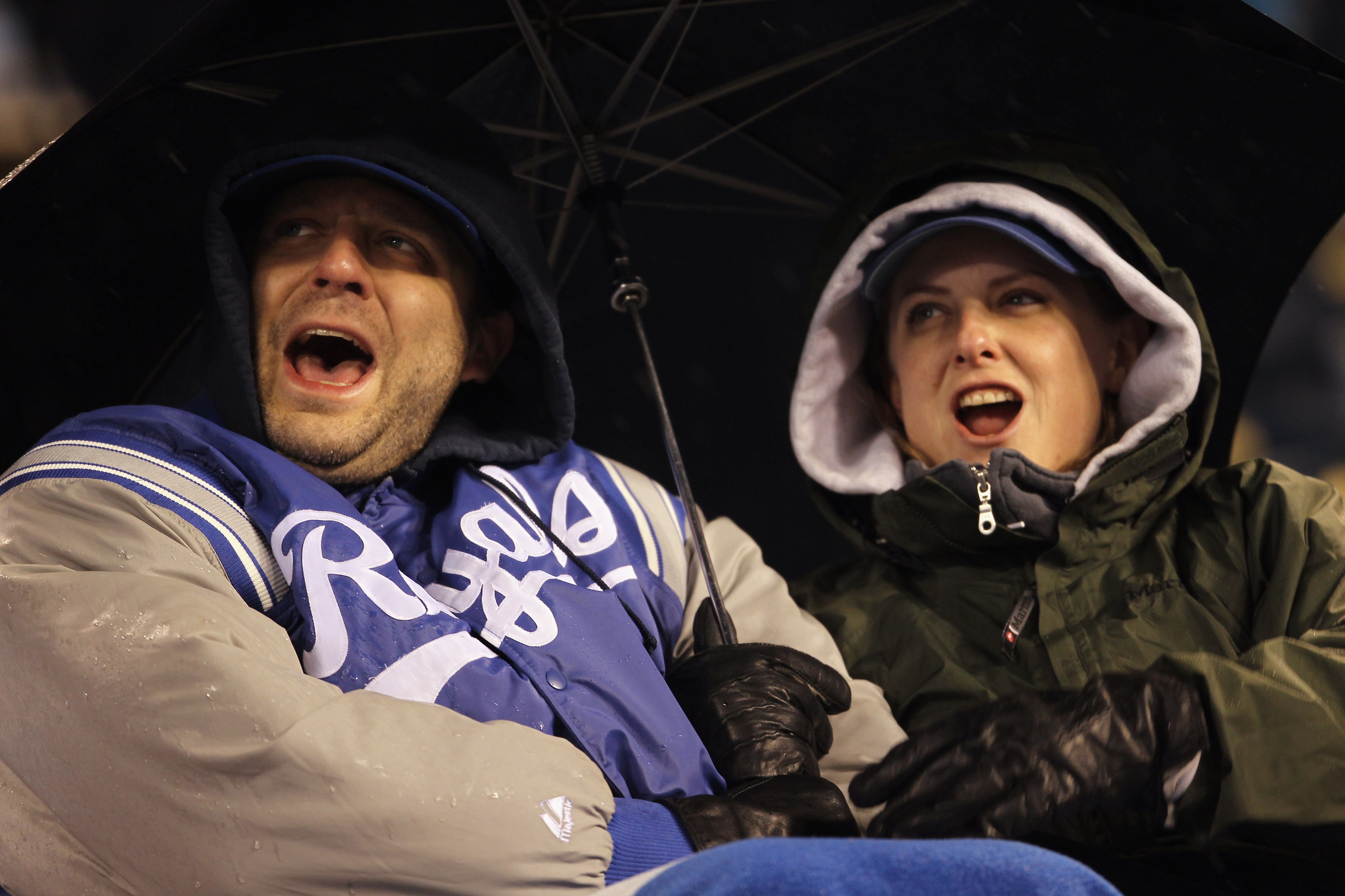 KANSAS CITY, MO - APRIL 15:  Fans cheer under an umbrella on a rainy night during the game between the Seattle Mariners and the Kansas City Royals at Kauffman Stadium on April 15, 2011 in Kansas City, Missouri.  (Photo by Jamie Squire/Getty Images)