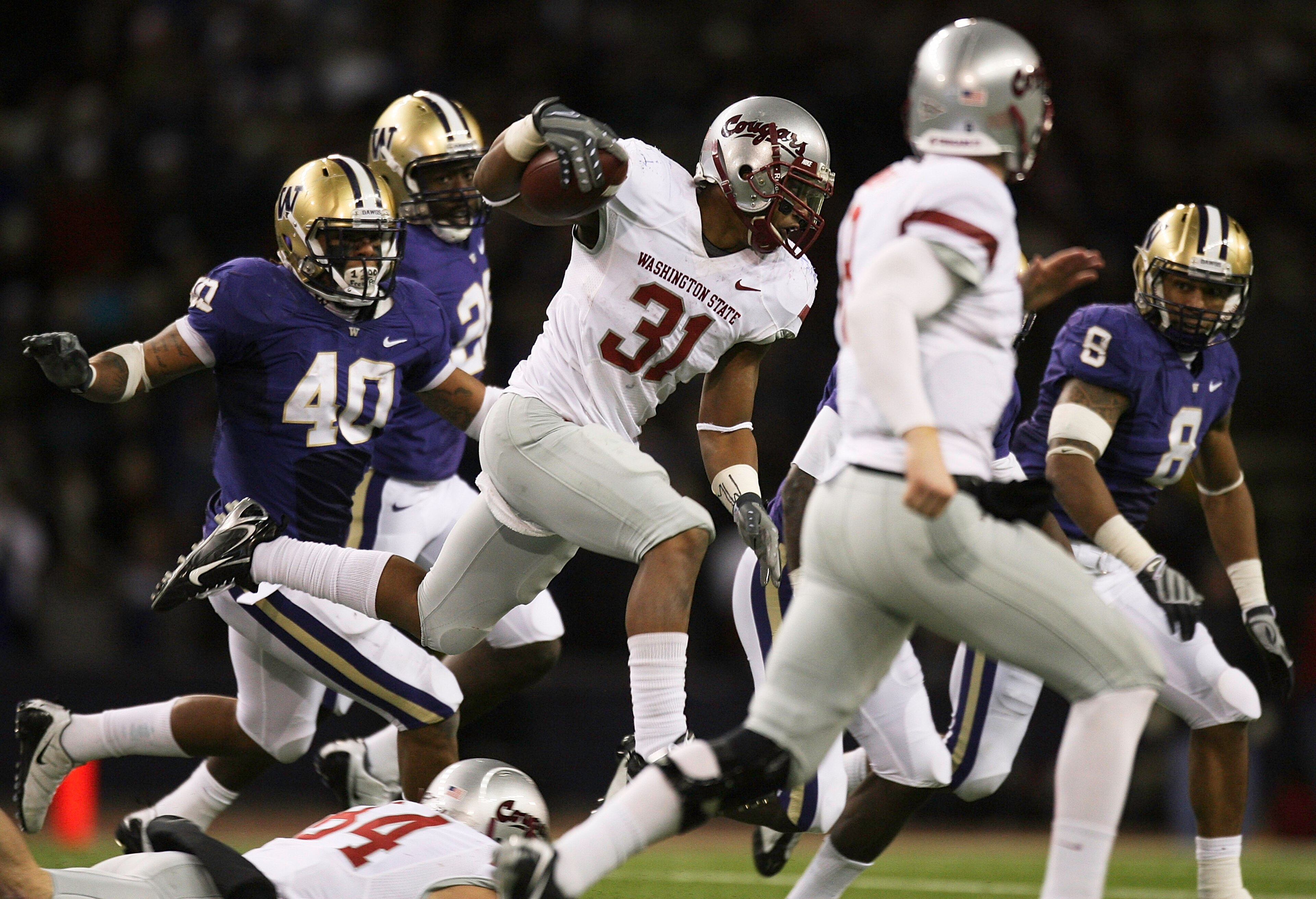 SEATTLE - NOVEMBER 28:  Running back Dwight Tardy #31 of the Washington State Cougars rushes against Mason Foster #40 and Nate Williams #8 of the Washington Huskies on November 28, 2009 at Husky Stadium in Seattle, Washington. The Huskies defeated the Cou