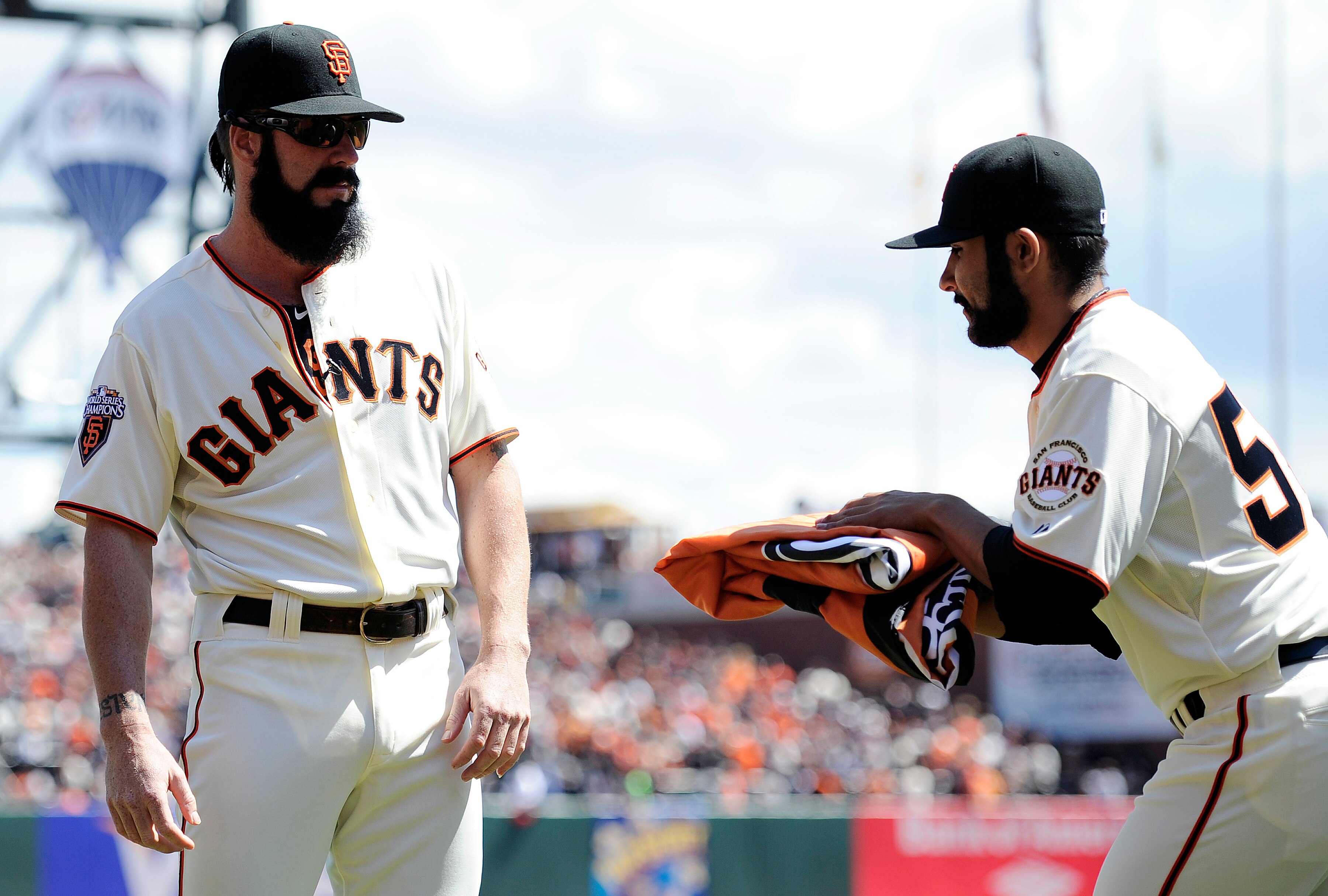 SAN FRANCISCO, CA - APRIL 8: Sergio Romo #54 of the San Francisco Giants hands off the 2010 Championship flag to closer Brian Wilson #38 prior to the start of the San Francisco Giants home opener against the St. Louis Cardinals at AT&T Park April 8, 2011