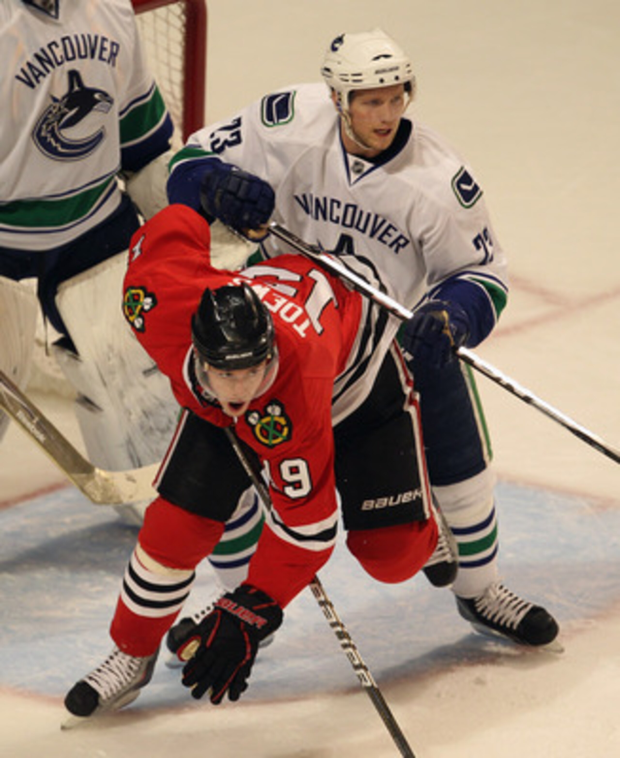 CHICAGO, IL - APRIL 17: Jonathan Toews #19 of the Chicago Blackhawks is knocked down by Alexander Edler #23 of the Vancouver Canucks in front of the Canucks goal in Game Three of the Western Conference Quarterfinals during the 2011 NHL Stanley Cup Playoff