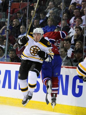 MONTREAL, CANADA - APRIL 26:  Brad Marchand #63 of the Boston Bruins throws a bodycheck on Travis Moen #32 of the Montreal Canadiens in behind the net in Game Six of the Eastern Conference Quarterfinals during the 2011 NHL Stanley Cup Playoffs at the Bell