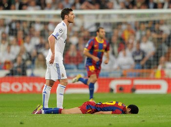 MADRID, SPAIN - APRIL 27:  Xabi Alonso (L) of Real Madrid stands besides Pedro Rodriguez of Barcelona laying on the pitch during the UEFA Champions League Semi Final first leg match between Real Madrid and Barcelona at the Estadio Santiago Bernabeu on Apr