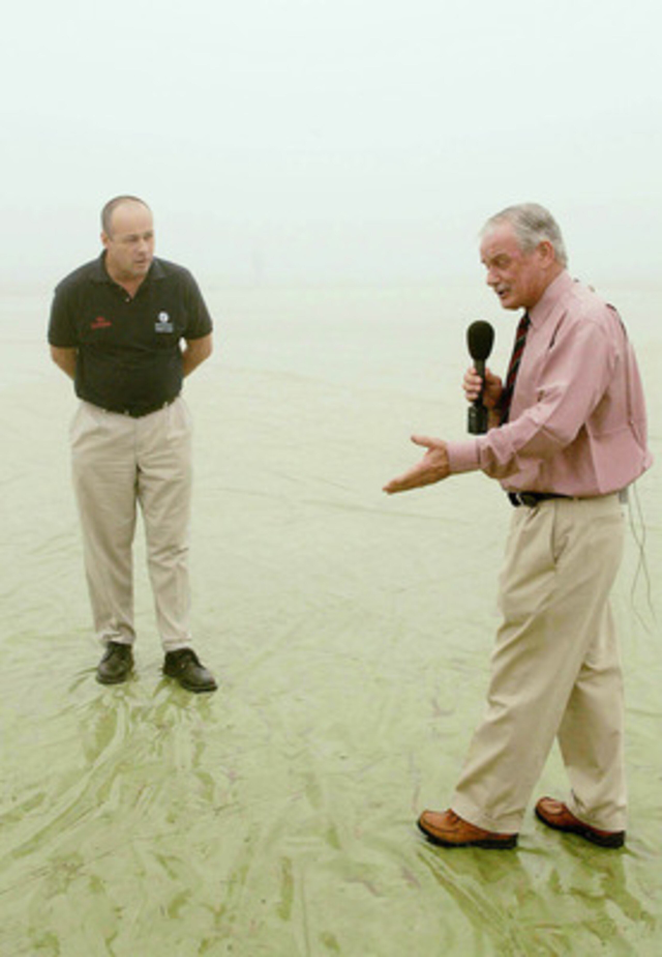 KANPUR, INDIA - NOVEMBER 22: (TOUCHLINE PHOTO IMAGES ARE AVAILABLE TO CLIENTS IN THE UK, USA AND AUSTRALIA ONLY)   Pitch reporter Robin Jackman talks with Umpire Daryl Harper in the fog during a delayed start on day three of the First test between India a