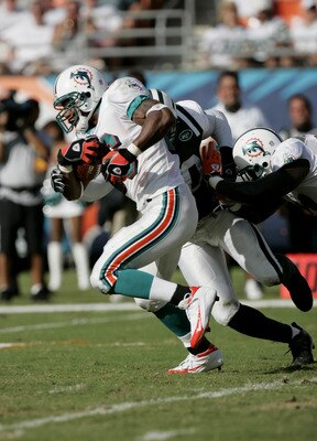 MIAMI - OCTOBER 3:  Runningback Leonard Henry #26 of the Miami Dolphins is nearly tackled by the New York Jets during the game at Pro Player Stadium on October  3, 2004 in Miami, Florida. The Jets won 17-9.  (Photo by Eliot J. Schechter/Getty Images)