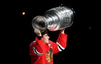 CHICAGO - OCTOBER 09: Jonathan Toews #19 of the Chicago Blackhawks carries the Stanley Cup trophy across the ice in a ceremony before the Blackhawks season home opening game against the Detroit Red Wings at the United Center on October 9, 2010 in Chicago,