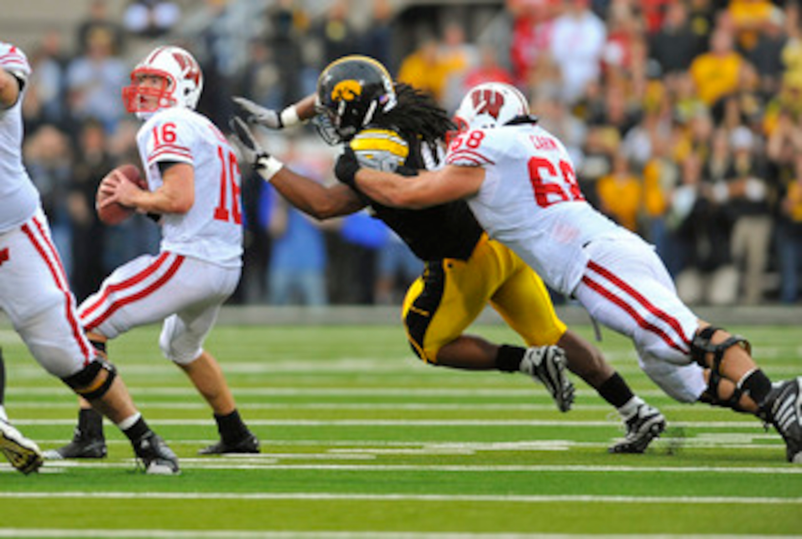 IOWA CITY, IA - OCTOBER 23- Quarterback Scott Tolzien #16 of the Wisconsin Badgers throws under pressure from Defensive lineman Adrian Clayborn #94 of the University of Iowa Hawkeyes as offensive lineman Gabe Carimi #68 defends during the first half of pl IOWA CITY, IA - OCTOBER 23- Quarterback Scott Tolzien #16 of the Wisconsin Badgers throws under pressure from Defensive lineman Adrian Clayborn #94 of the University of Iowa Hawkeyes as offensive lineman Gabe Carimi #68 defends during the first half of pl