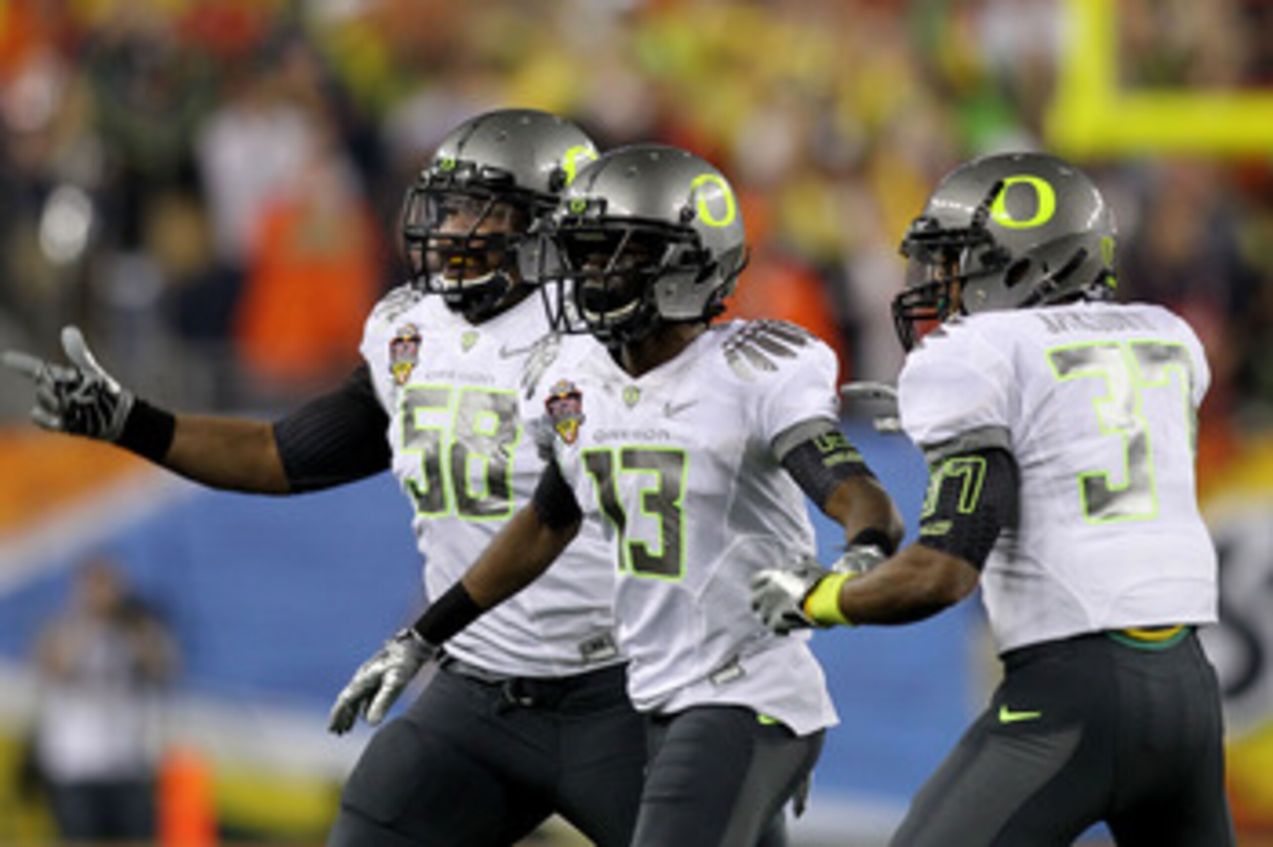 GLENDALE, AZ - JANUARY 10:  Cliff Harris #13 of the Oregon Ducks celebrates his first quarter interception with teammates Drew Howell #50 and Talmadge Jackson III #37 against the Auburn Tigers during the Tostitos BCS National Championship Game at Universi