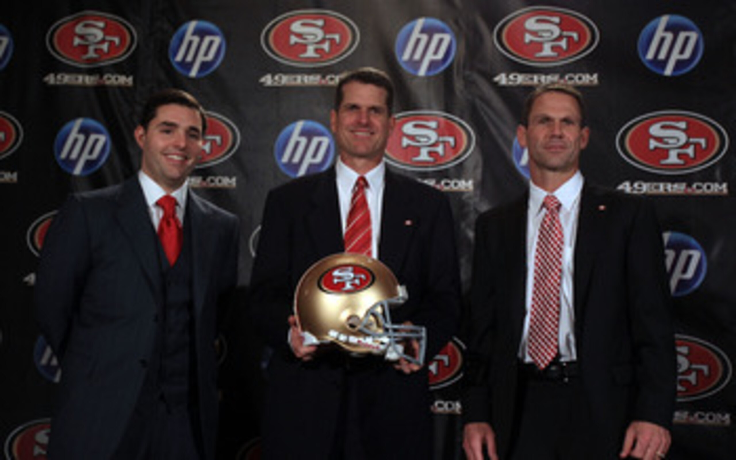 SAN FRANCISCO, CA - JANUARY 07:  Jim Harbaugh poses for a picture with President and CEO of the San Francisco 49ers, Jed York, (left) and general manager Trent Baalk following a press conference where Harbaugh was introduced as the new San Francisco 49ers