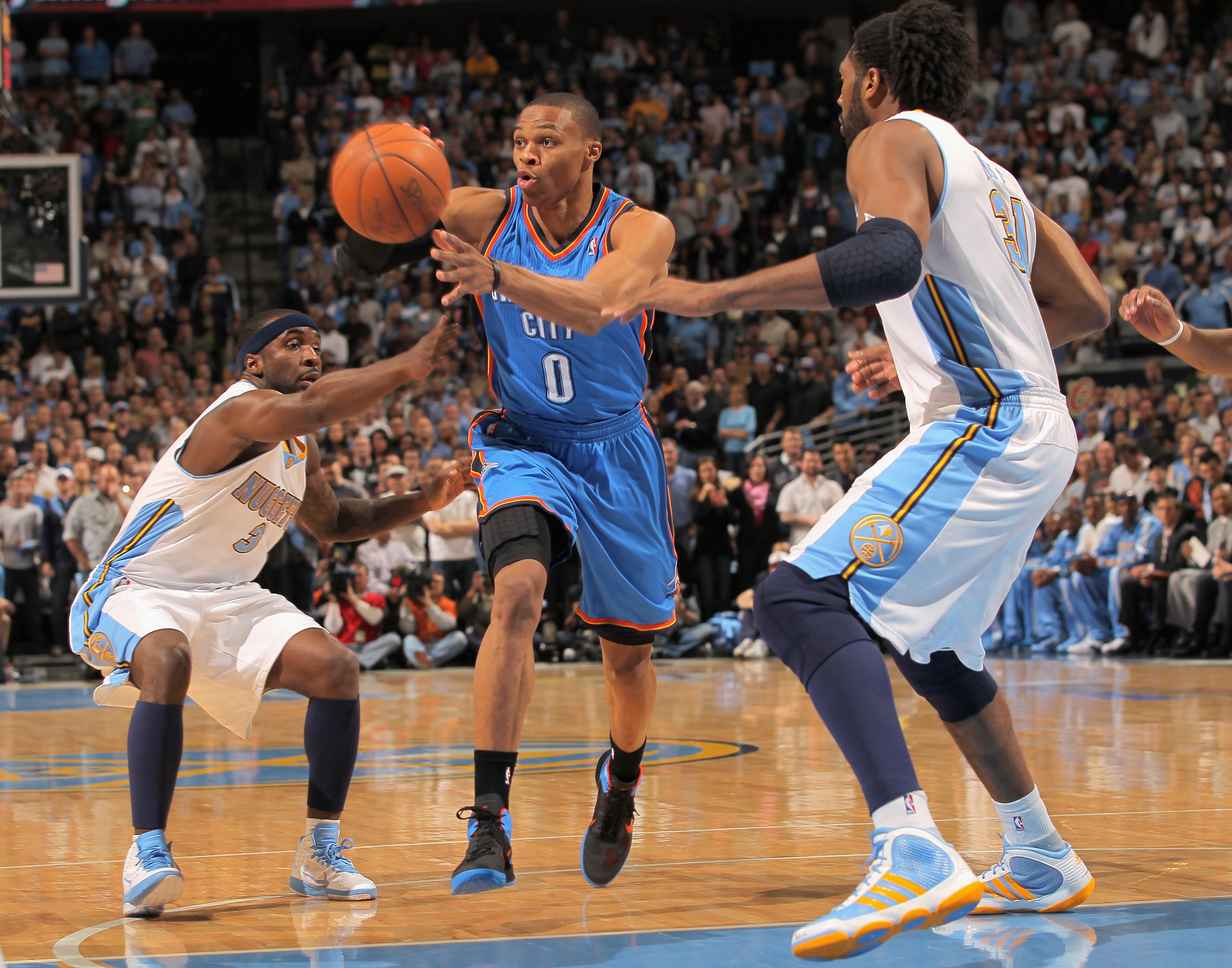 DENVER, CO - APRIL 23: Russell Westbrook #0 of the Oklahoma City Thunder dishes off a pass between Ty Lawson #3 and Nene Hilario #31 of the Denver Nuggets in Game Three of the Western Conference Quarterfinals in the 2011 NBA Playoffs on April 23, 2011 at