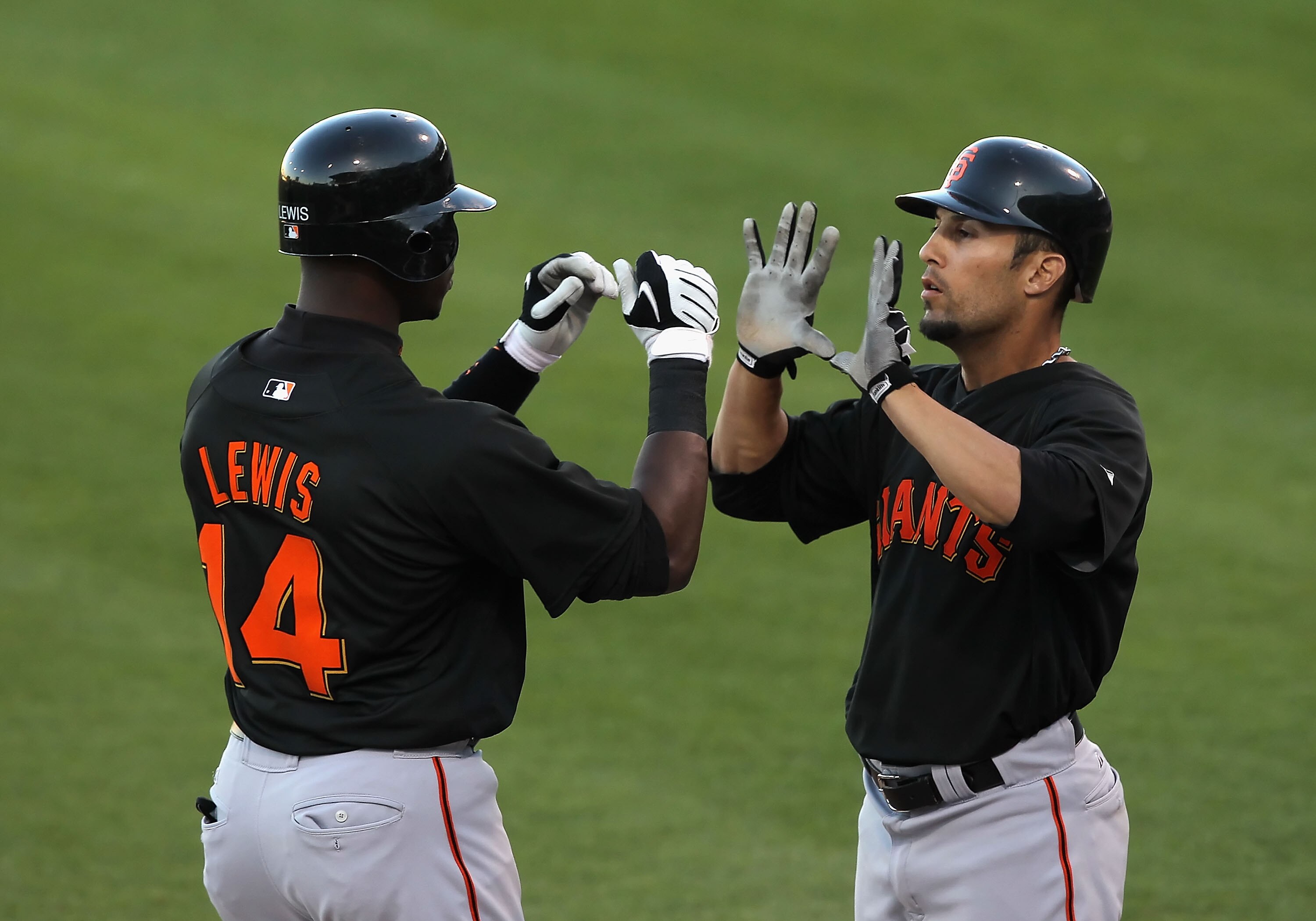 SURPRISE, AZ - MARCH 15:  Fred Lewis #14 of the San Francisco Giants is congratulated by teammate Andres Torres #13 after Lewis hit a 2 run home run against the Texas Rangers during the first inning of the MLB spring training game at Surprise Stadium on M