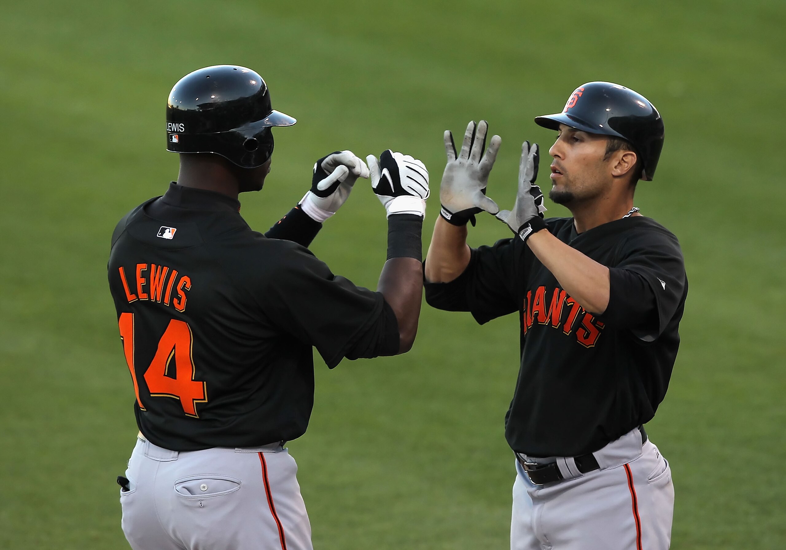 SURPRISE, AZ - MARCH 15:  Fred Lewis #14 of the San Francisco Giants is congratulated by teammate Andres Torres #13 after Lewis hit a 2 run home run against the Texas Rangers during the first inning of the MLB spring training game at Surprise Stadium on M