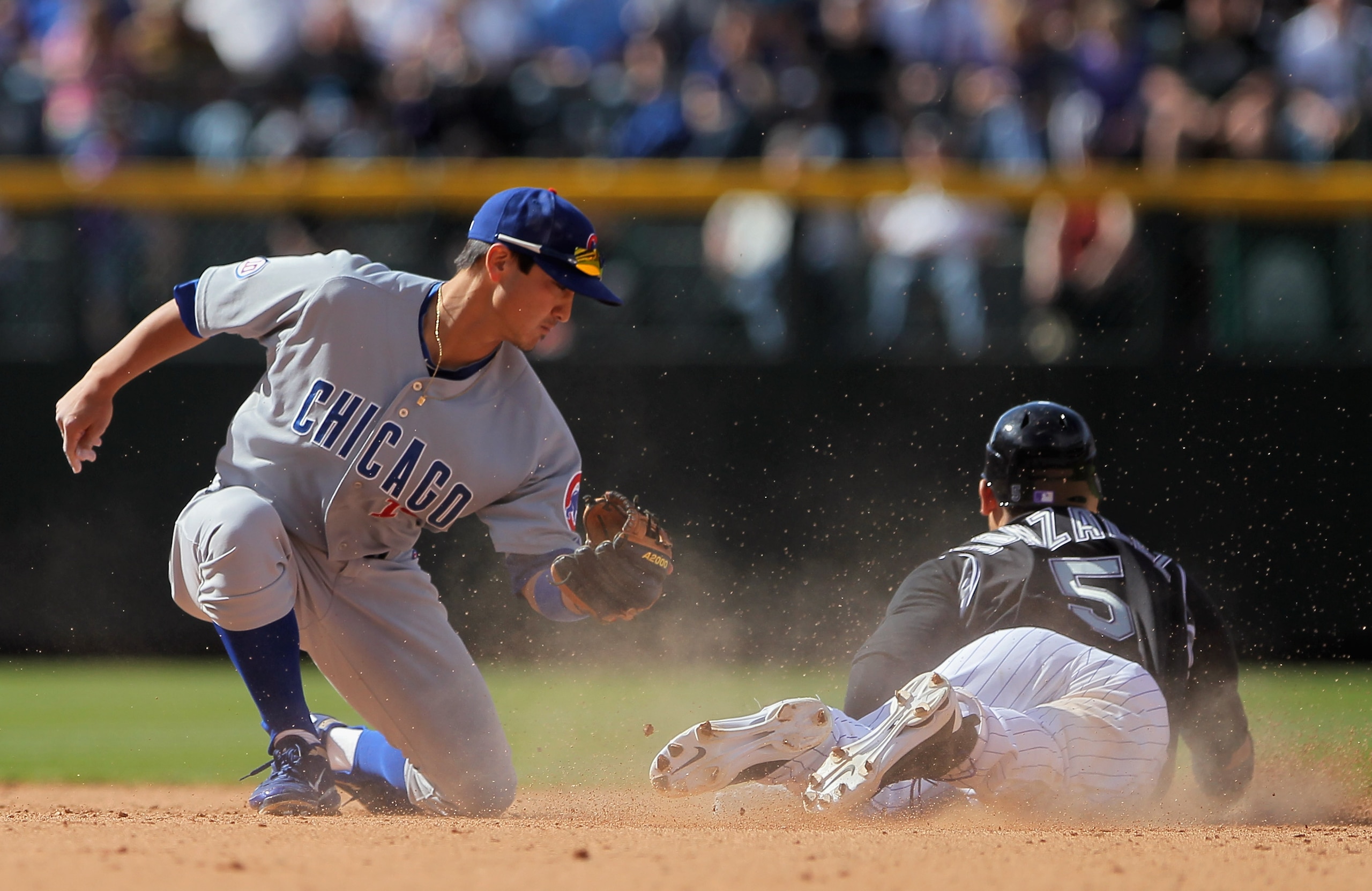 DENVER, CO - APRIL 17:  Carlos Gonzalez #5 of the Colorado Rockies slides in safely as he steals  second base ahead of the tag from second baseman Darwin Barney #15 of the Chicago Cubs at Coors Field on April 17, 2011 in Denver, Colorado.  (Photo by Doug