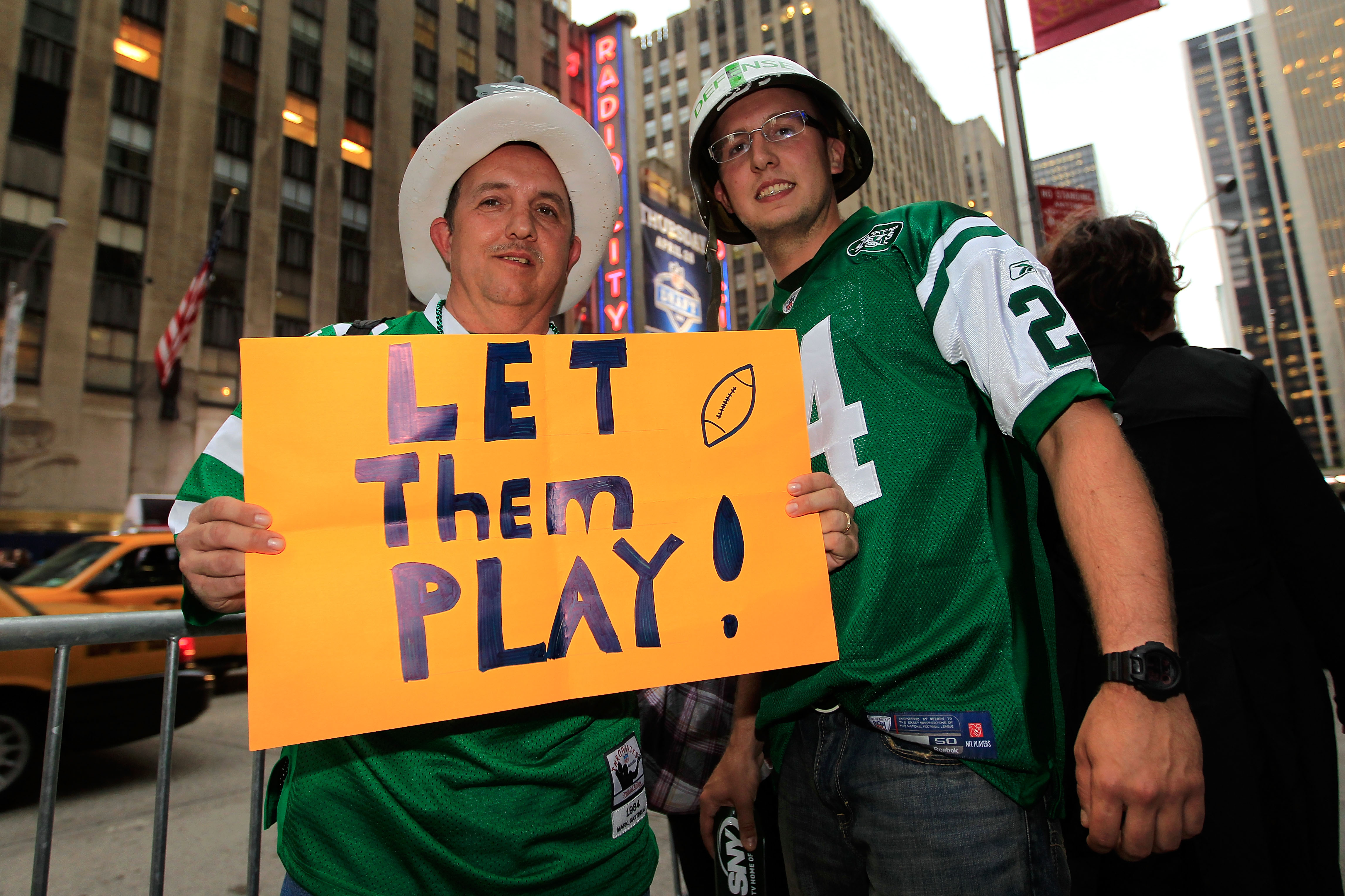 NEW YORK, NY - APRIL 28:  New York Jets fans Peter Merante Sr. and his son Peter Jr. hold up a sign which reads 'Let them play!' on the street outside the venue prior to the 2011 NFL Draft at Radio City Music Hall on April 28, 2011 in New York City.  (Pho