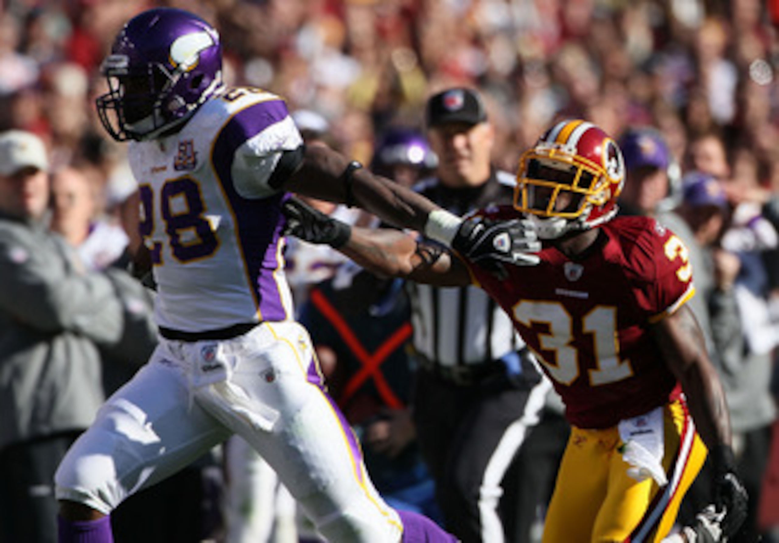 LANDOVER, MD - NOVEMBER 28: Running back Adrian Peterson #28 of the Minnesota Vikings stiff arms Philip Buchanon #31 the Washington Redskins at FedExField November 28, 2010 in Landover, Maryland. The Vikings won the game 17-13. (Photo by Win McNamee/Getty