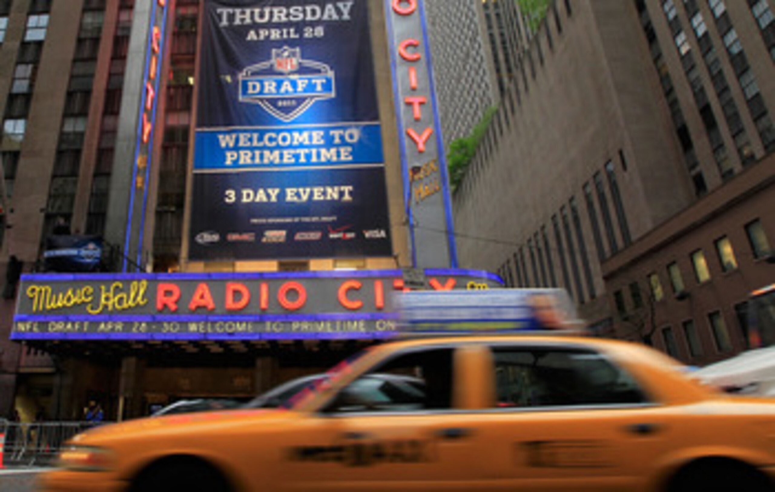 NEW YORK, NY - APRIL 28:  Taxi cabs drive down the Avenue of the Americas past the Radio City Music Hall marquee, site of the 2011 NFL Draft, on April 28, 2011 in New York City.  (Photo by Chris Trotman/Getty Images)