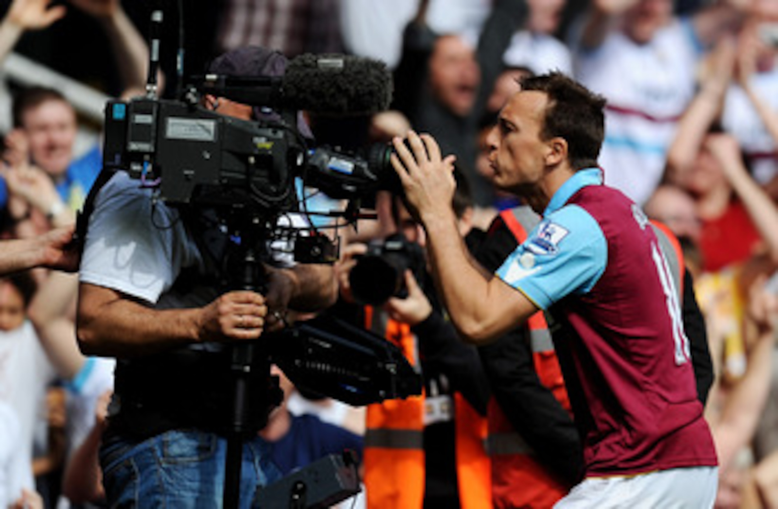 LONDON, ENGLAND - APRIL 02: Mark Noble of West Ham United celebrates scoring his penalty with a TV cameraman during the Barclays Premier League match between West Ham United and Manchester United at the Boleyn Ground on April 2, 2011 in London, England. LONDON, ENGLAND - APRIL 02: Mark Noble of West Ham United celebrates scoring his penalty with a TV cameraman during the Barclays Premier League match between West Ham United and Manchester United at the Boleyn Ground on April 2, 2011 in London, England.