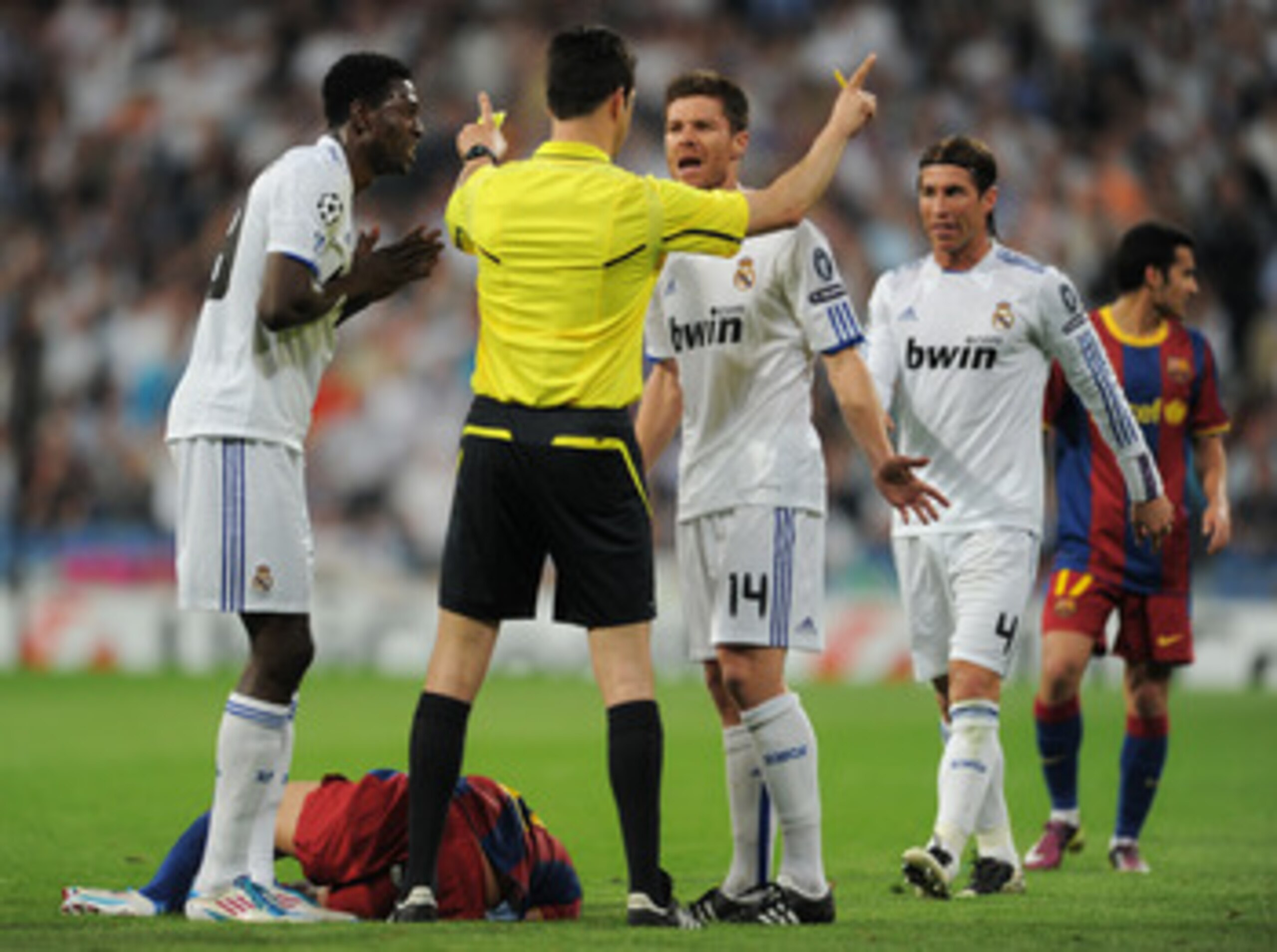 MADRID, SPAIN - APRIL 27:  Emmanuel Adebayor (L) and Xabi Alonso (R) of Real Madrid argue with referee Wolfgang Stark (C) as Daniel Alves of Barcelona lays on the pitch and Sergio Ramos looks on during the UEFA Champions League Semi Final first leg match