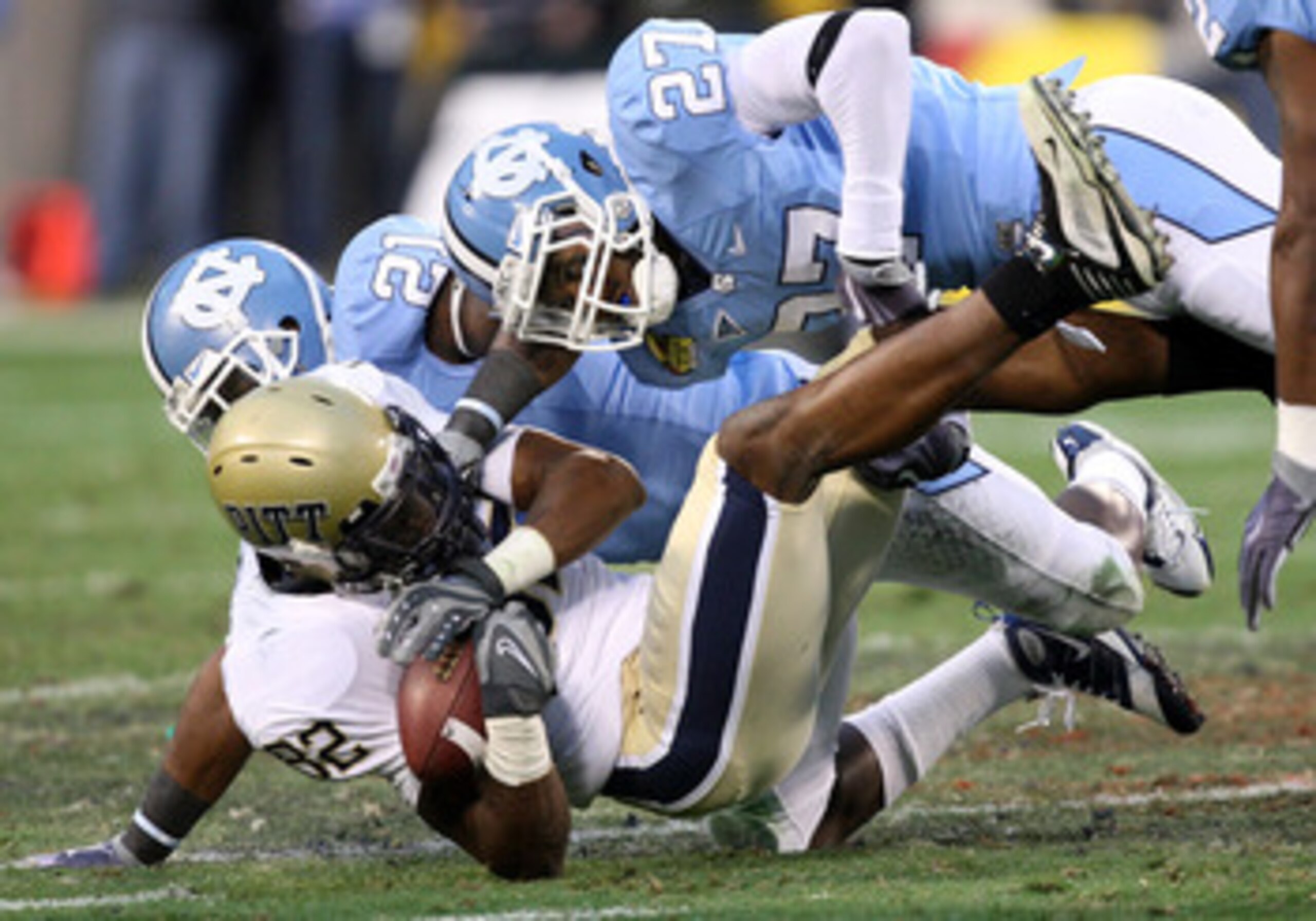 CHARLOTTE, NC - DECEMBER 26:  Jonathan Baldwin #82 of the Pittsburgh Panthers is tackled by teammates Da'Norris Searcy #21 and Deunta Williams #27 of the North Carolina Tar Heels during their game on December 26, 2009 in Charlotte, North Carolina.  (Photo