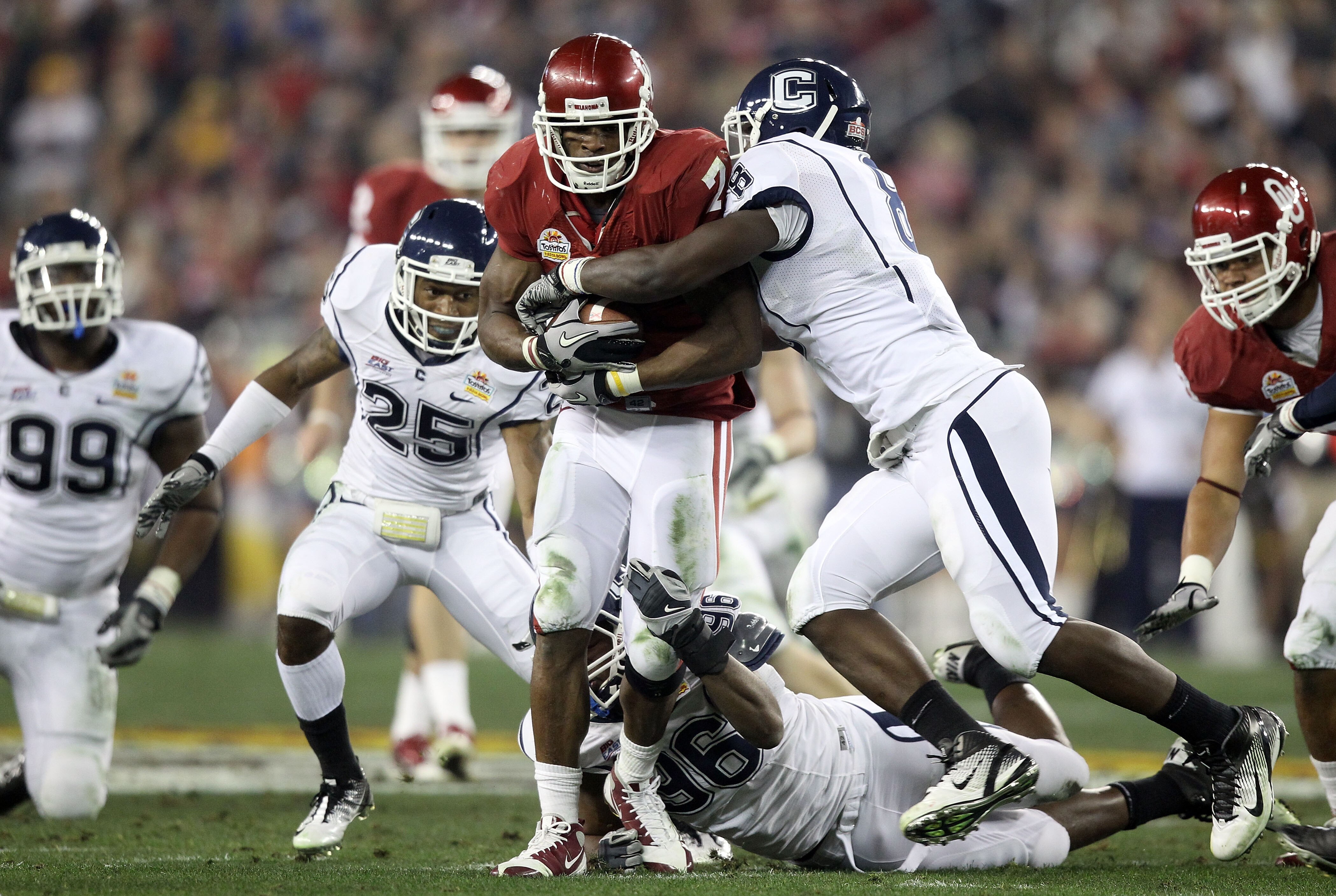 GLENDALE, AZ - JANUARY 01:  DeMarco Murray #7 of the Oklahoma Sooners runs the ball as he is hit bu Lawrence Wilson #8 of the Connecticut Huskies in the second quarter during the Tostitos Fiesta Bowl at the Universtity of Phoenix Stadium on January 1, 201