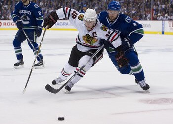 VANCOUVER, CANADA - APRIL 26: Keith Ballard #4 of the Vancouver Canucks and Jonathan Toews #19 of the Chicago Blackhawks battle for the loose puck during the first period in Game Seven of the Western Conference Quarterfinals during the 2011 NHL Stanley Cu