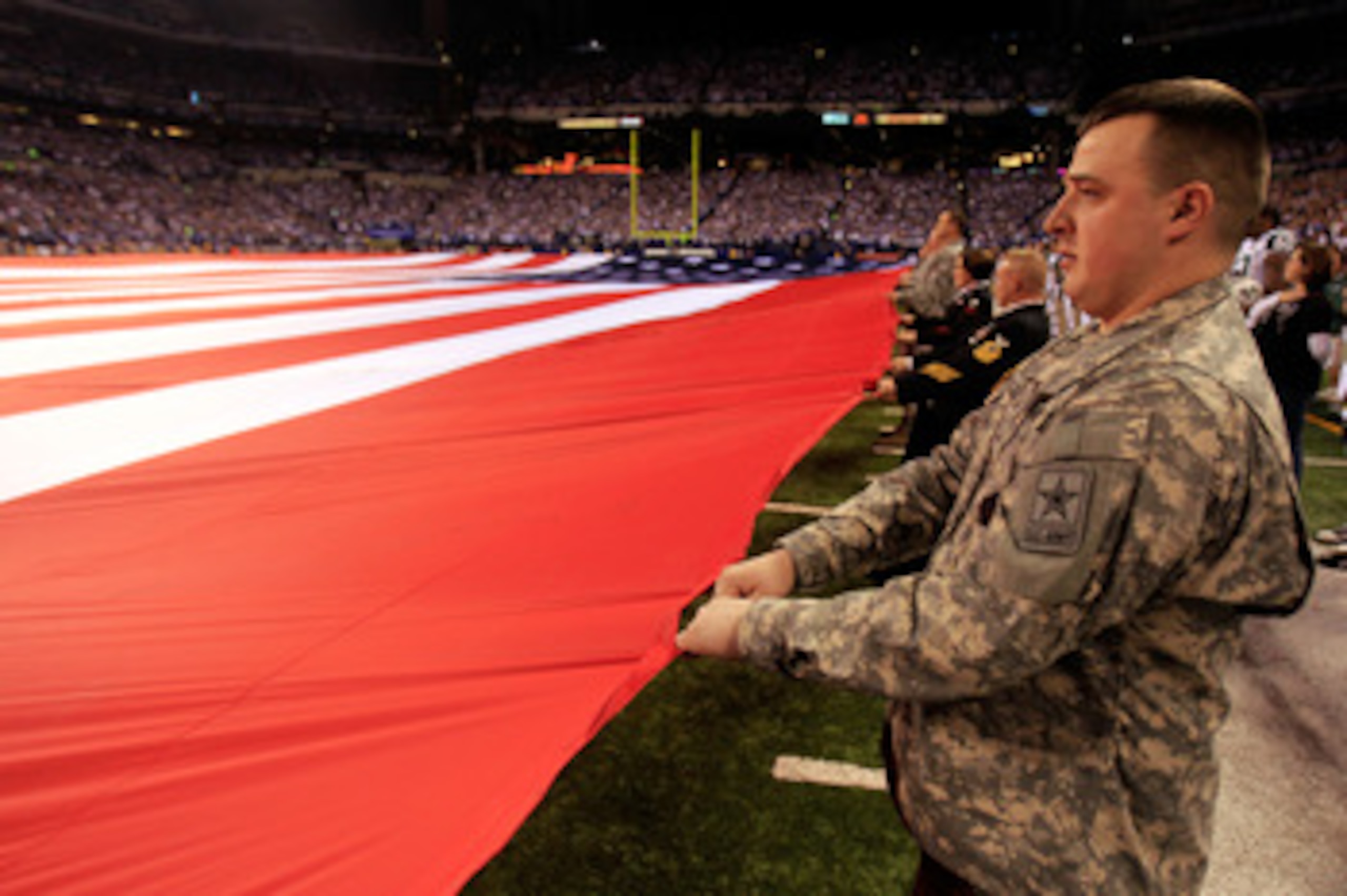 INDIANAPOLIS, IN - JANUARY 08: Military personnel stretch out a giant AMerican Flag for the performance of the Nation Anthem prior to the Indianapolis Colts hosting the New York Jets during their 2011 AFC wild card playoff game at Lucas Oil Stadium on Ja INDIANAPOLIS, IN - JANUARY 08: Military personnel stretch out a giant AMerican Flag for the performance of the Nation Anthem prior to the Indianapolis Colts hosting the New York Jets during their 2011 AFC wild card playoff game at Lucas Oil Stadium on Ja