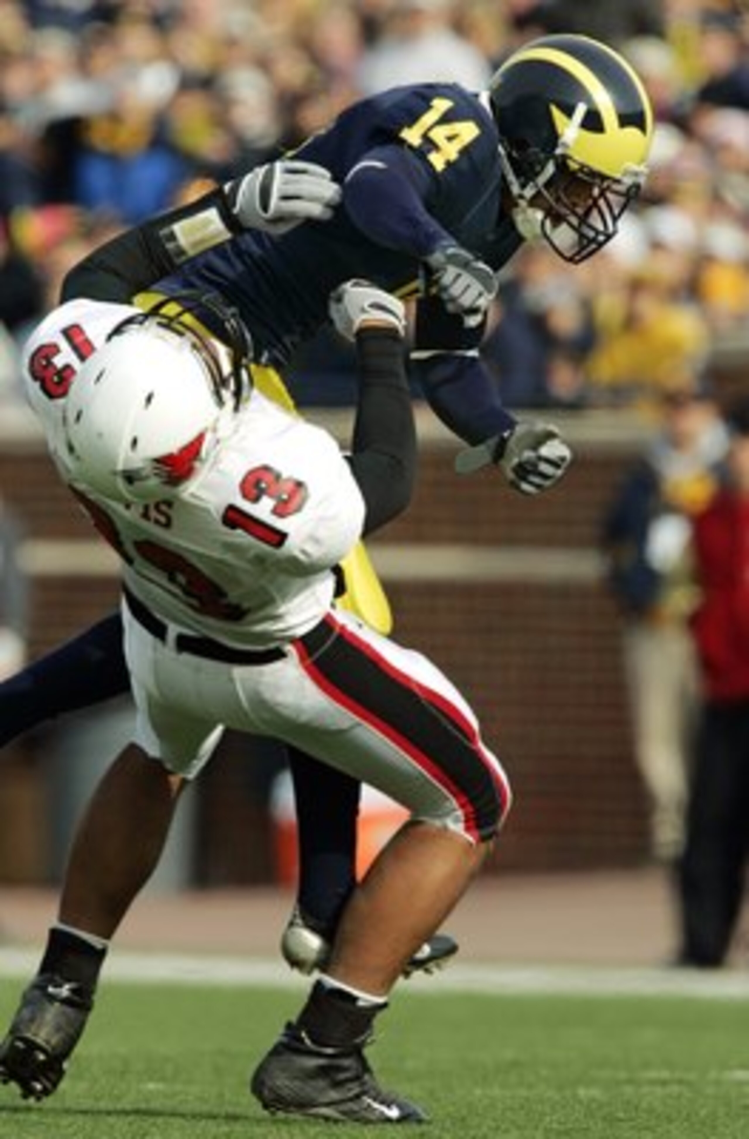 ANN ARBOR, MI - NOVEMBER 4:  Quarterback Nate Davis #13 of the Ball State Cardinals gets off a pass for 13 yards and then picks up another 15 yards on the personal foul by cornerback Morgan Trent #14 of the Michigan Wolverines in the first quarter on Nove